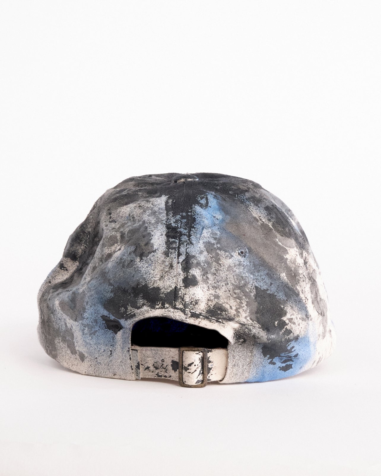 Back of of Black Vuori baseball hat customized by ASTROBOI* with blue and black painted details, stainless steel piercings, and an embroidered V logo.