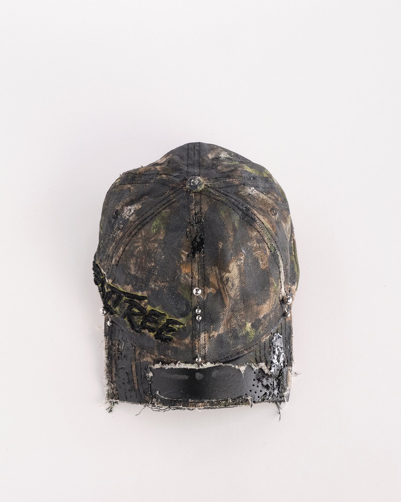 Top of Brown RealTree distressed half-visor hat with elastic base, black resin detailing, and a sawed-off visor for a deconstructed Y2K aesthetic.