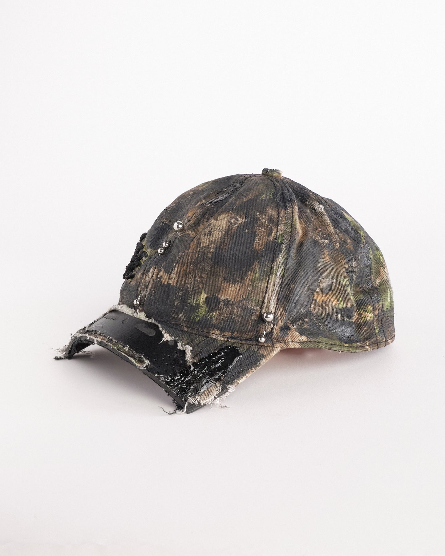 Left side of Brown RealTree distressed half-visor hat with elastic base, black resin detailing, and a sawed-off visor for a deconstructed Y2K aesthetic.