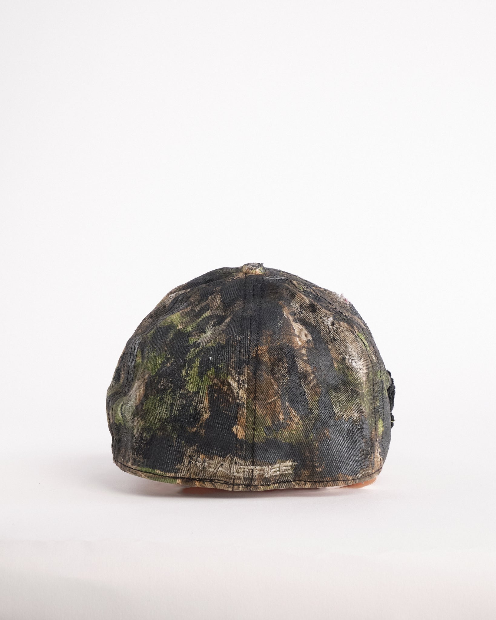 Back of Brown RealTree distressed half-visor hat with elastic base, black resin detailing, and a sawed-off visor for a deconstructed Y2K aesthetic.