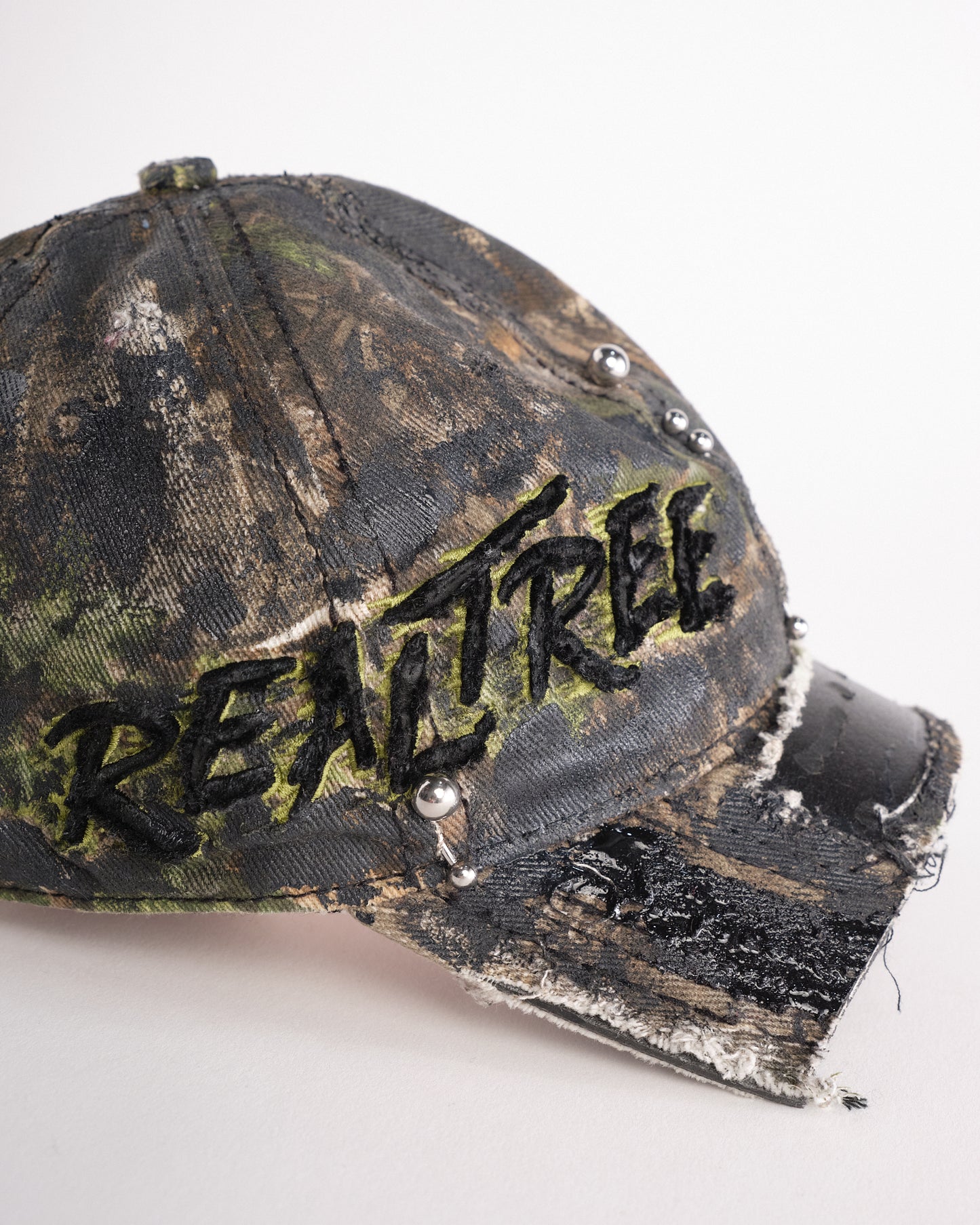 Right side of Brown RealTree distressed half-visor hat with elastic base, black resin detailing, and a sawed-off visor for a deconstructed Y2K aesthetic.