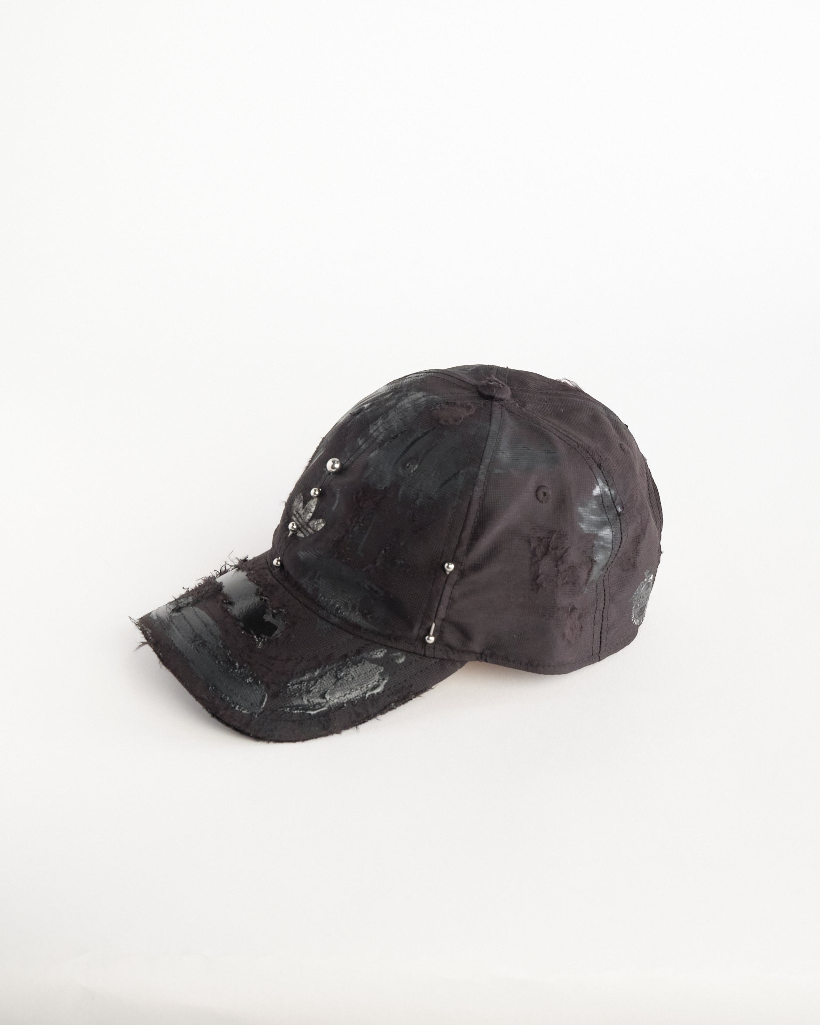 Left of Black Adidas hat customized by ASTROBOI* with distressing, black painted accents, and stainless steel piercings.