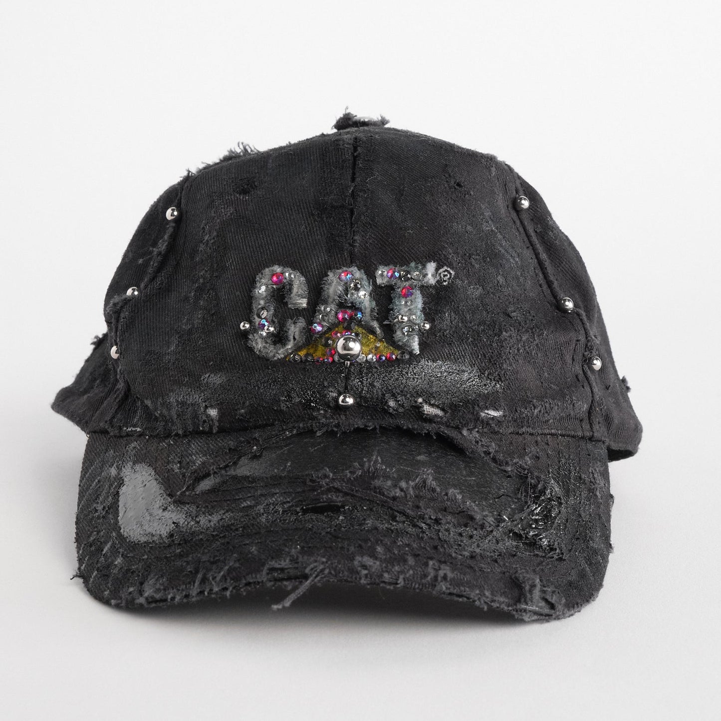 Front of ASTROBOI* x CAT black distressed pierced hat with rhinestone logo, resin and paint detailing, deconstructed visor, adjustable strap, handmade in NYC.