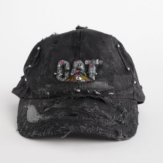 Front of ASTROBOI* x CAT black distressed pierced hat with rhinestone logo, resin and paint detailing, deconstructed visor, adjustable strap, handmade in NYC.
