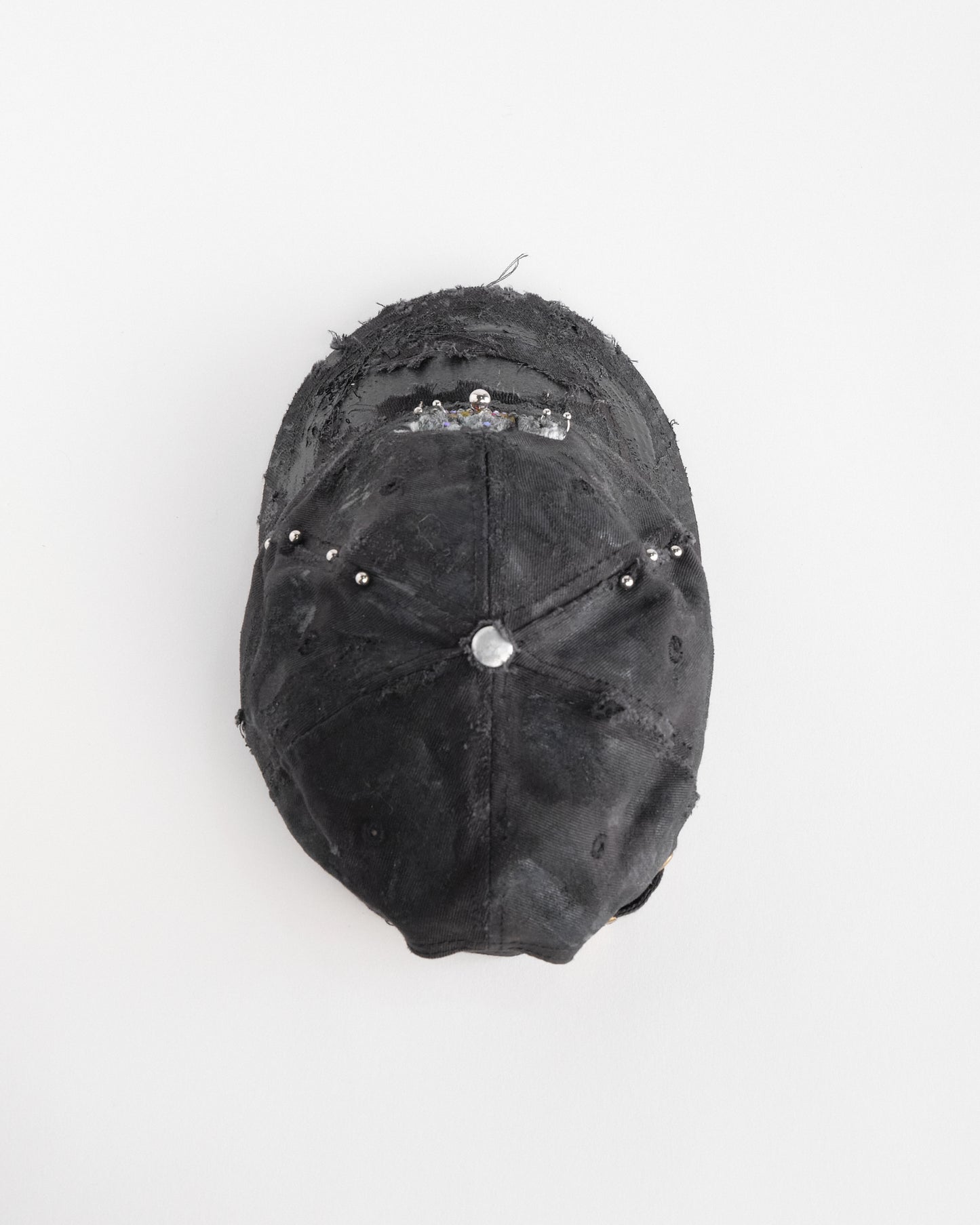 Back top of ASTROBOI* x CAT black distressed pierced hat with rhinestone logo, resin and paint detailing, deconstructed visor, adjustable strap, handmade in NYC.