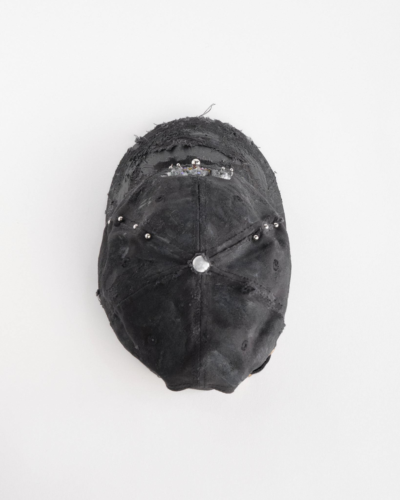 Back top of ASTROBOI* x CAT black distressed pierced hat with rhinestone logo, resin and paint detailing, deconstructed visor, adjustable strap, handmade in NYC.