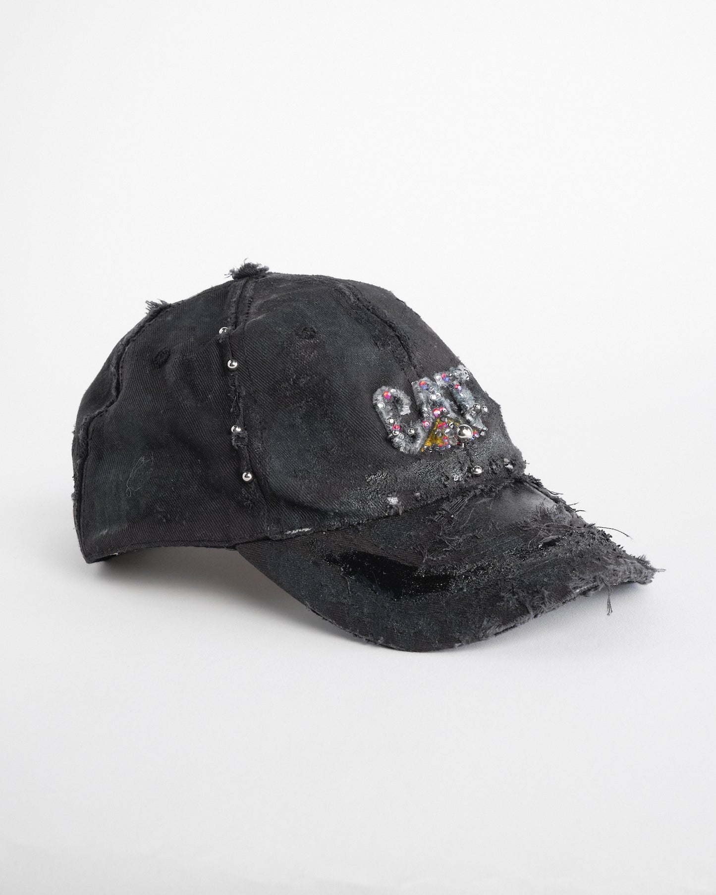 Right side of ASTROBOI* x CAT black distressed pierced hat with rhinestone logo, resin and paint detailing, deconstructed visor, adjustable strap, handmade in NYC.