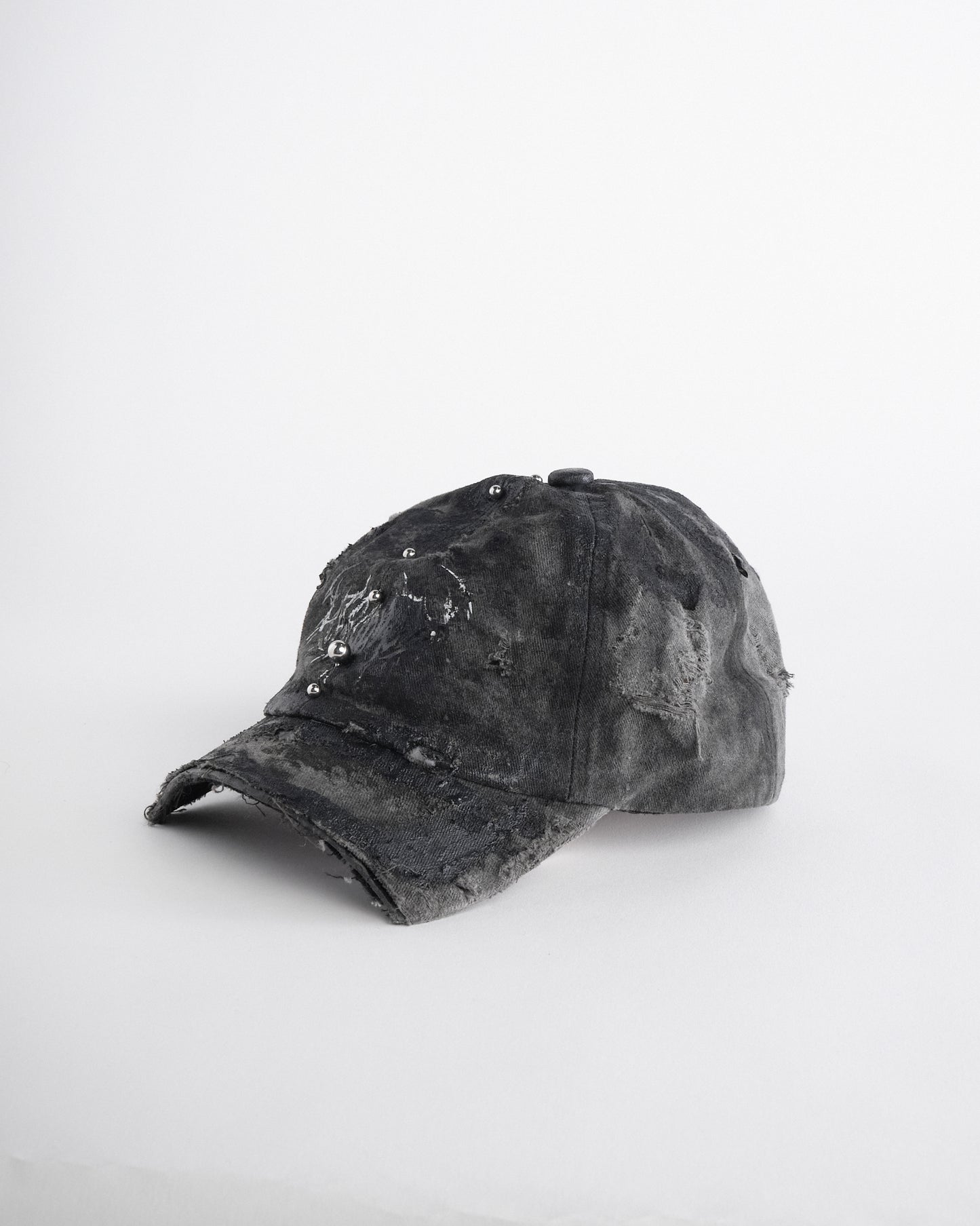 Left of Black distressed half-visor hat with barbed-wire logo, adjustable strap, black paint details, and stainless steel piercings along the brim.