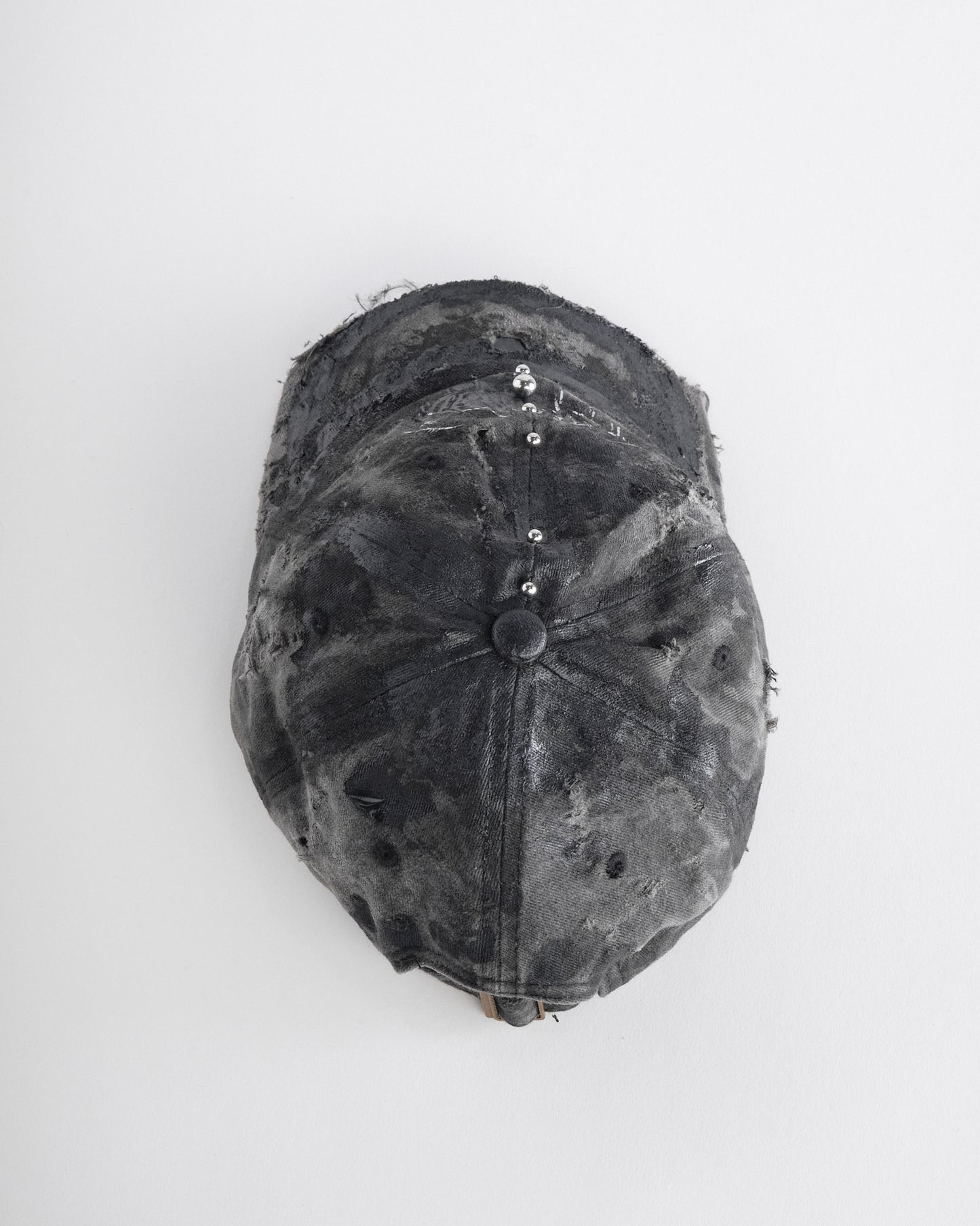 Top of Black distressed half-visor hat with barbed-wire logo, adjustable strap, black paint details, and stainless steel piercings along the brim.