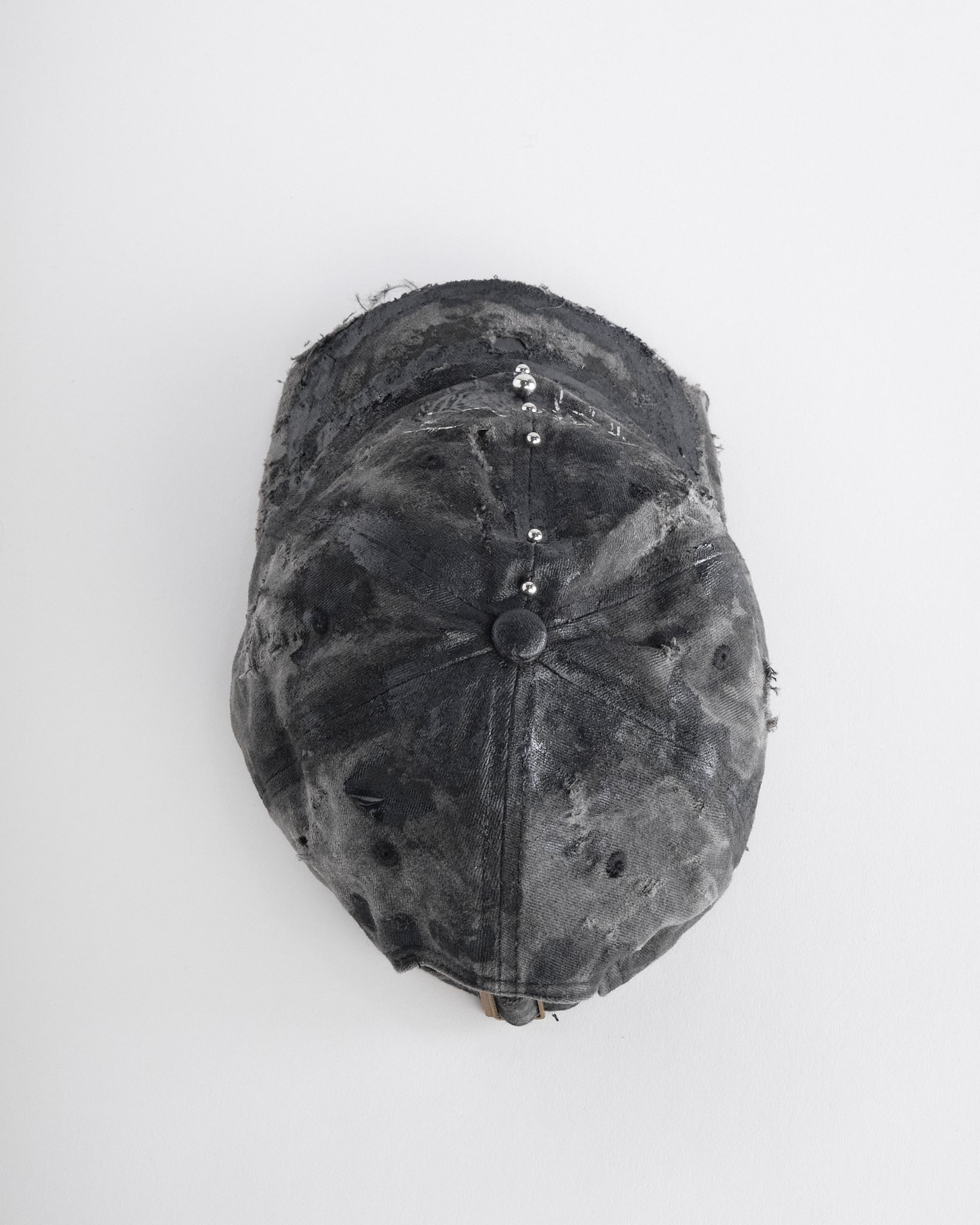 Top of Black distressed half-visor hat with barbed-wire logo, adjustable strap, black paint details, and stainless steel piercings along the brim.