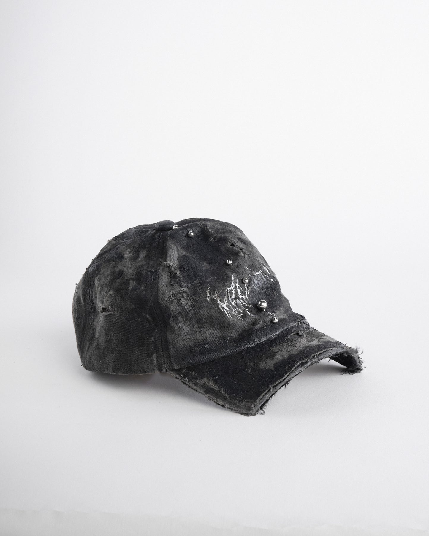 Right side of Black distressed half-visor hat with barbed-wire logo, adjustable strap, black paint details, and stainless steel piercings along the brim.