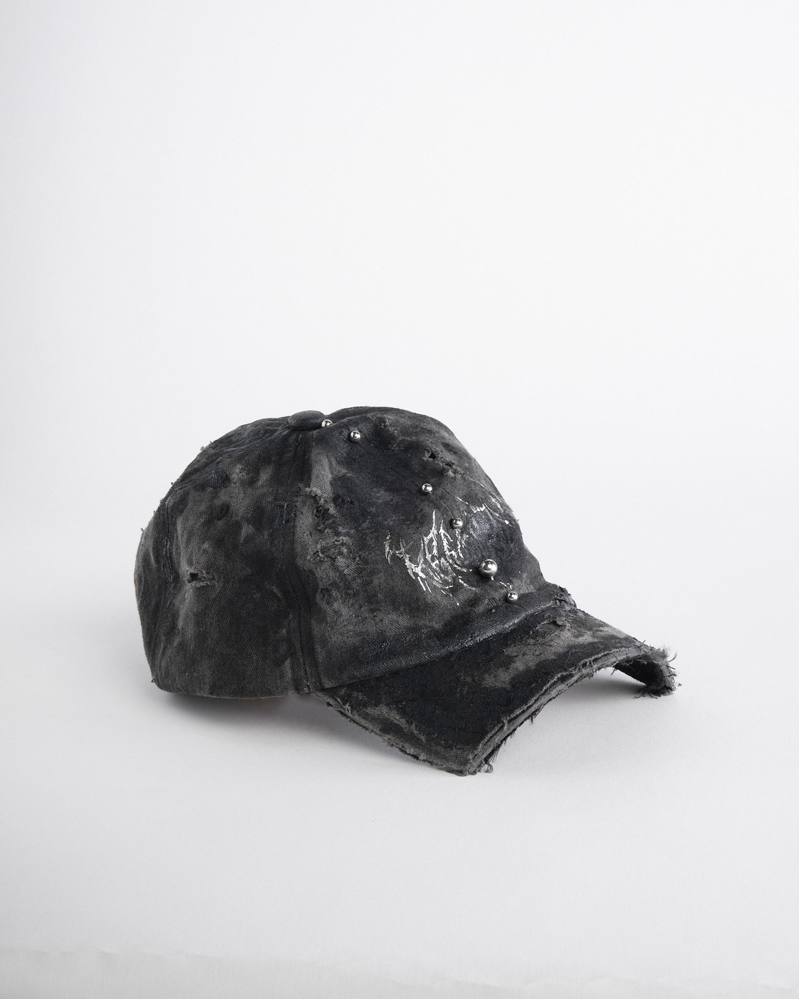 Right side of Black distressed half-visor hat with barbed-wire logo, adjustable strap, black paint details, and stainless steel piercings along the brim.