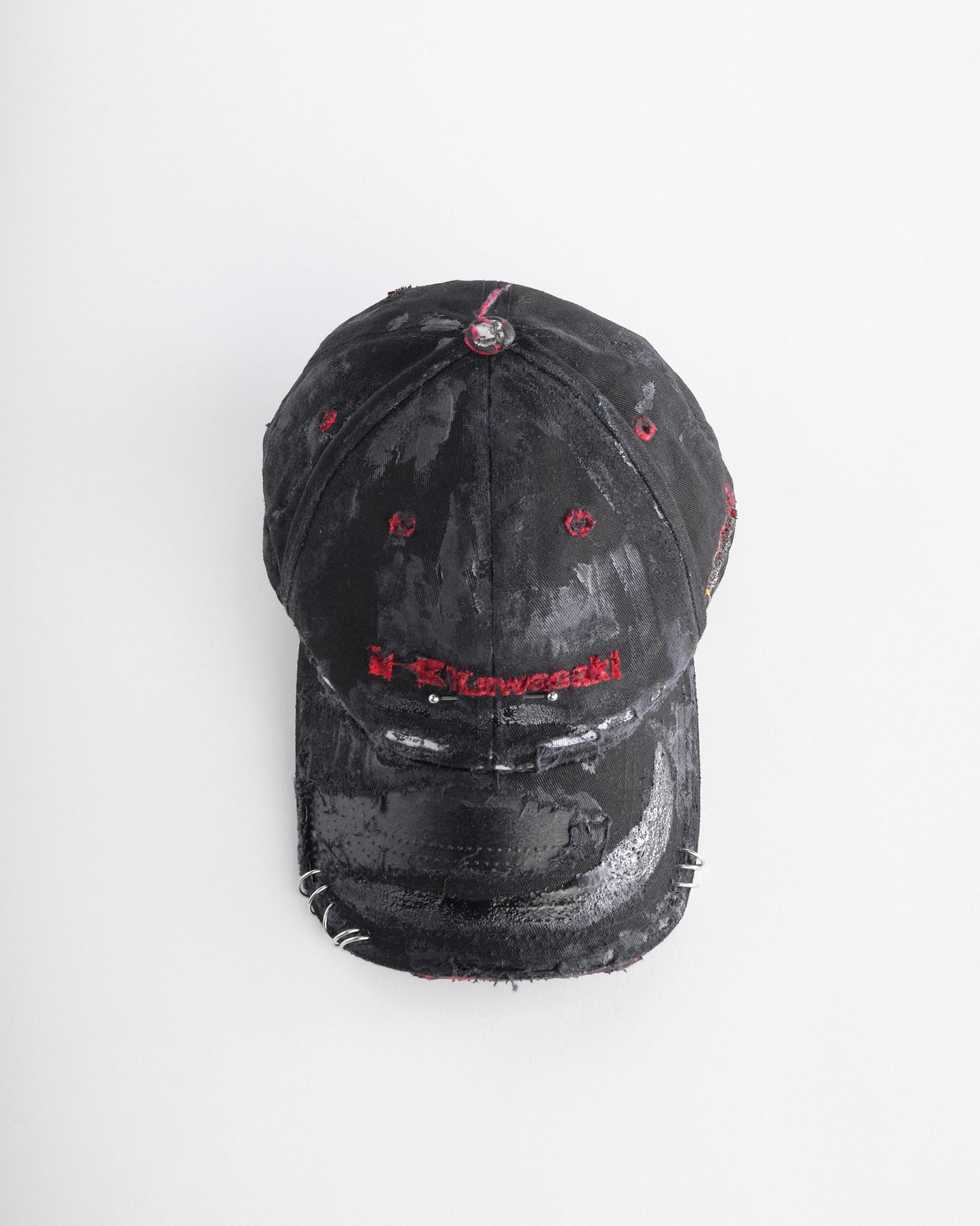 Top of ASTROBOI* x Kawasaki black distressed hat with pierced logo, deconstructed visor, stainless steel piercings, adjustable strap, handmade in NYC.