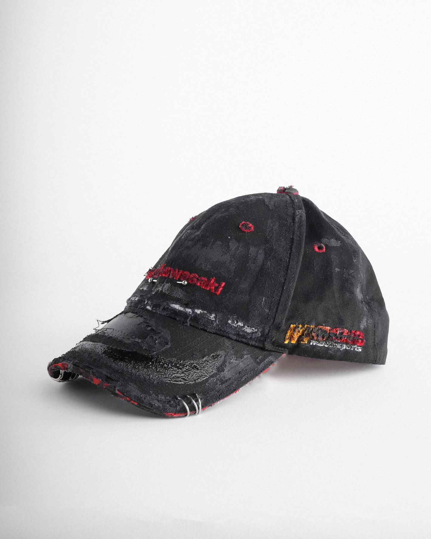 Left side of ASTROBOI* x Kawasaki black distressed hat with pierced logo, deconstructed visor, stainless steel piercings, adjustable strap, handmade in NYC.