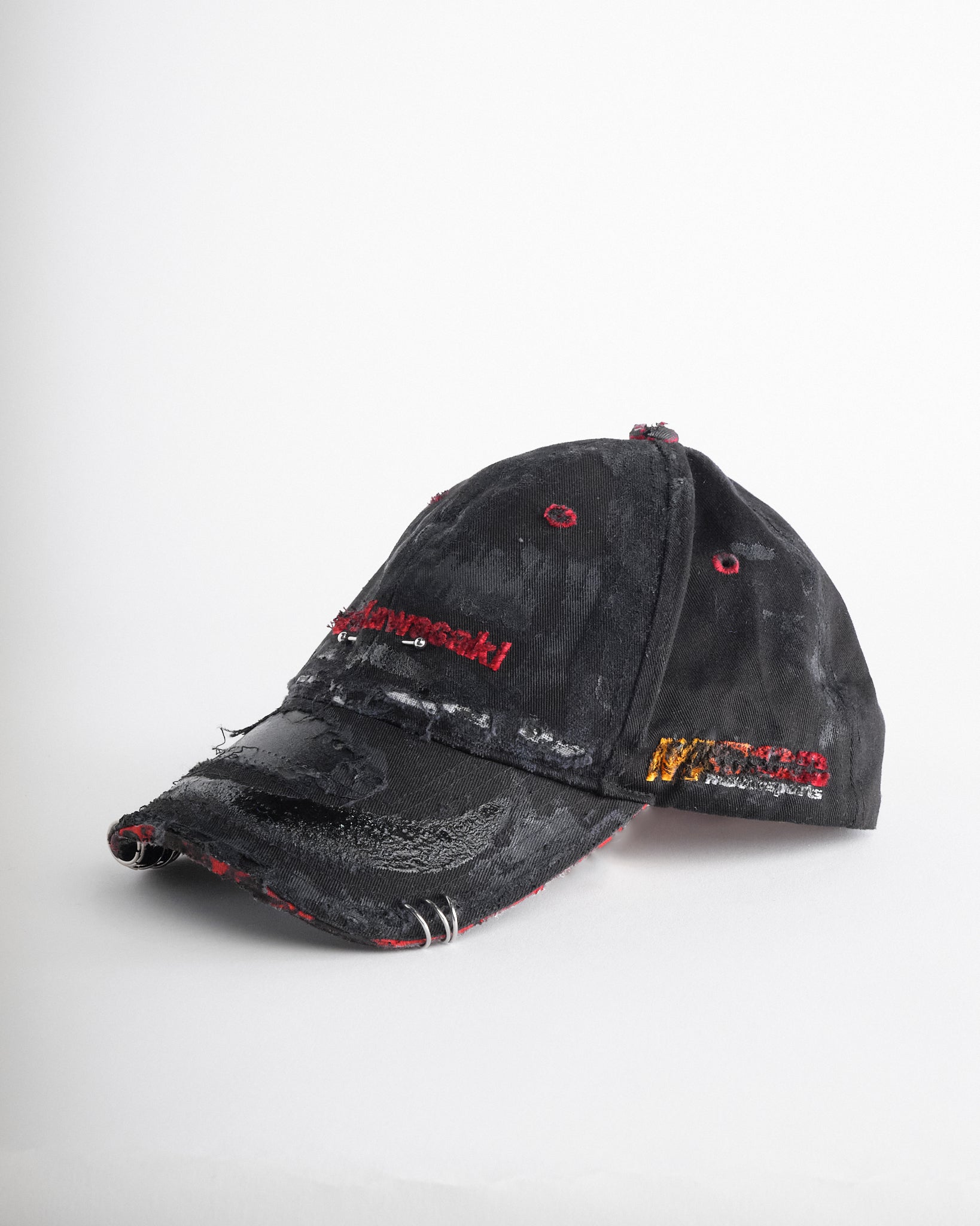 Left side of ASTROBOI* x Kawasaki black distressed hat with pierced logo, deconstructed visor, stainless steel piercings, adjustable strap, handmade in NYC.
