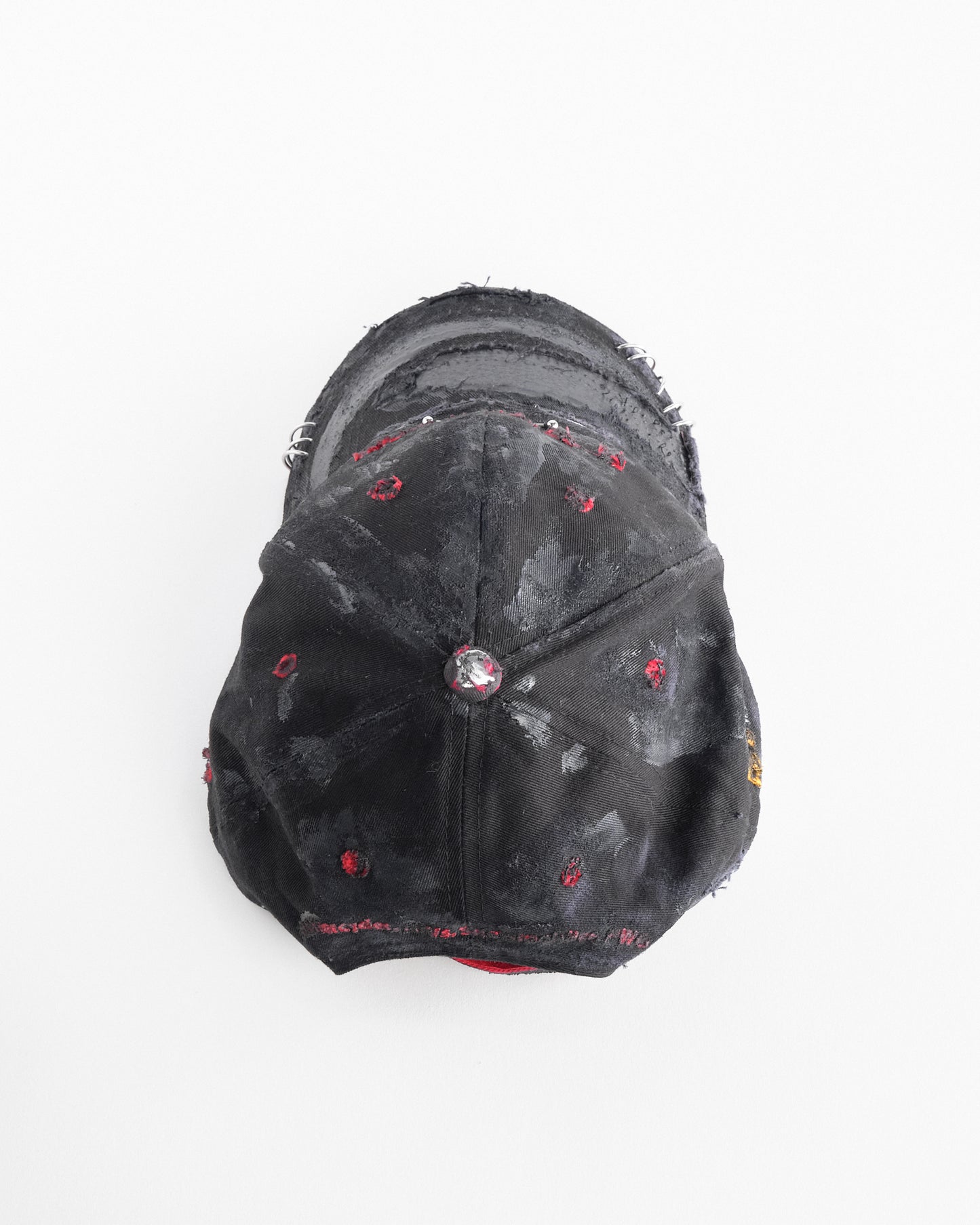 Top of ASTROBOI* x Kawasaki black distressed hat with pierced logo, deconstructed visor, stainless steel piercings, adjustable strap, handmade in NYC.