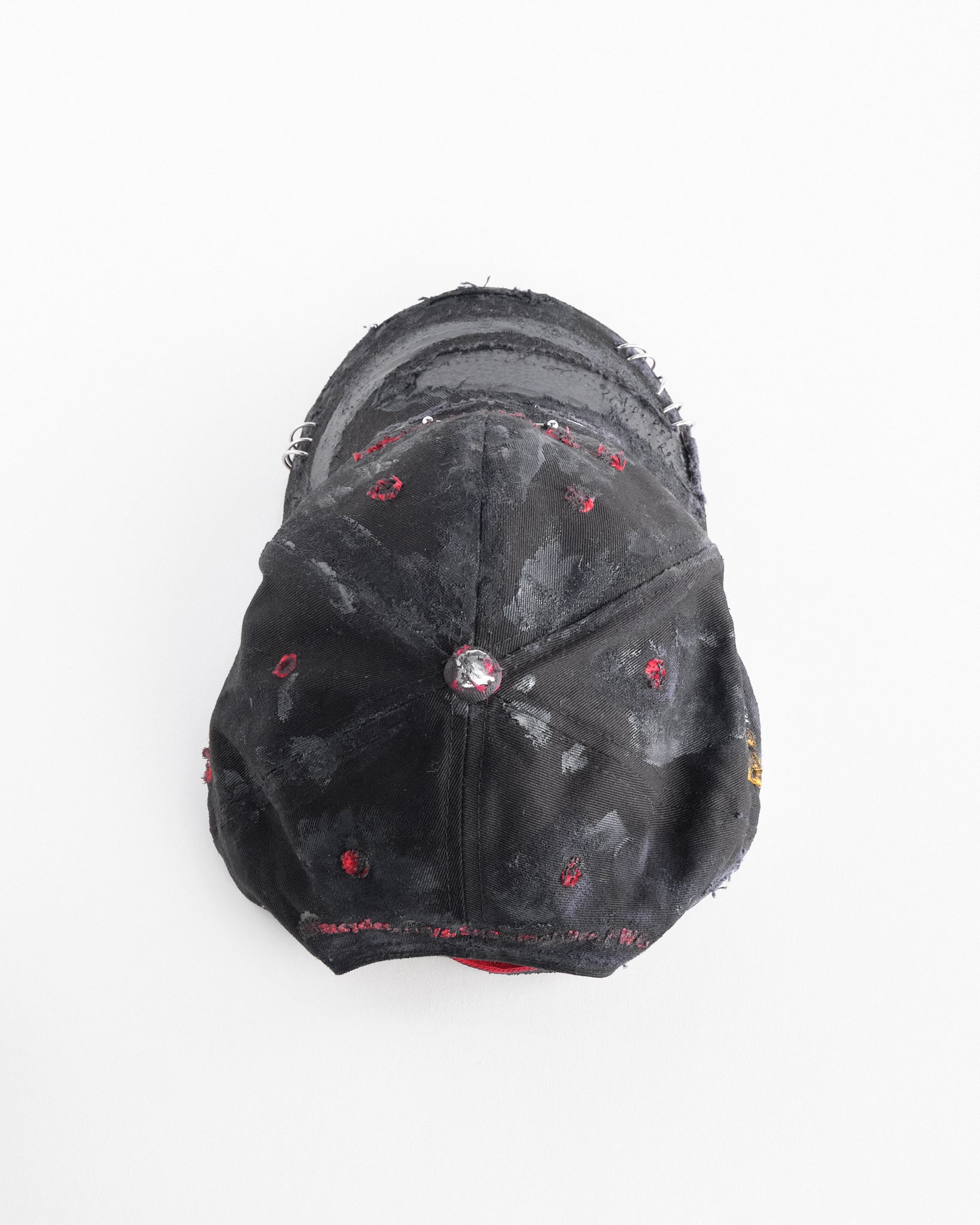 Top of ASTROBOI* x Kawasaki black distressed hat with pierced logo, deconstructed visor, stainless steel piercings, adjustable strap, handmade in NYC.
