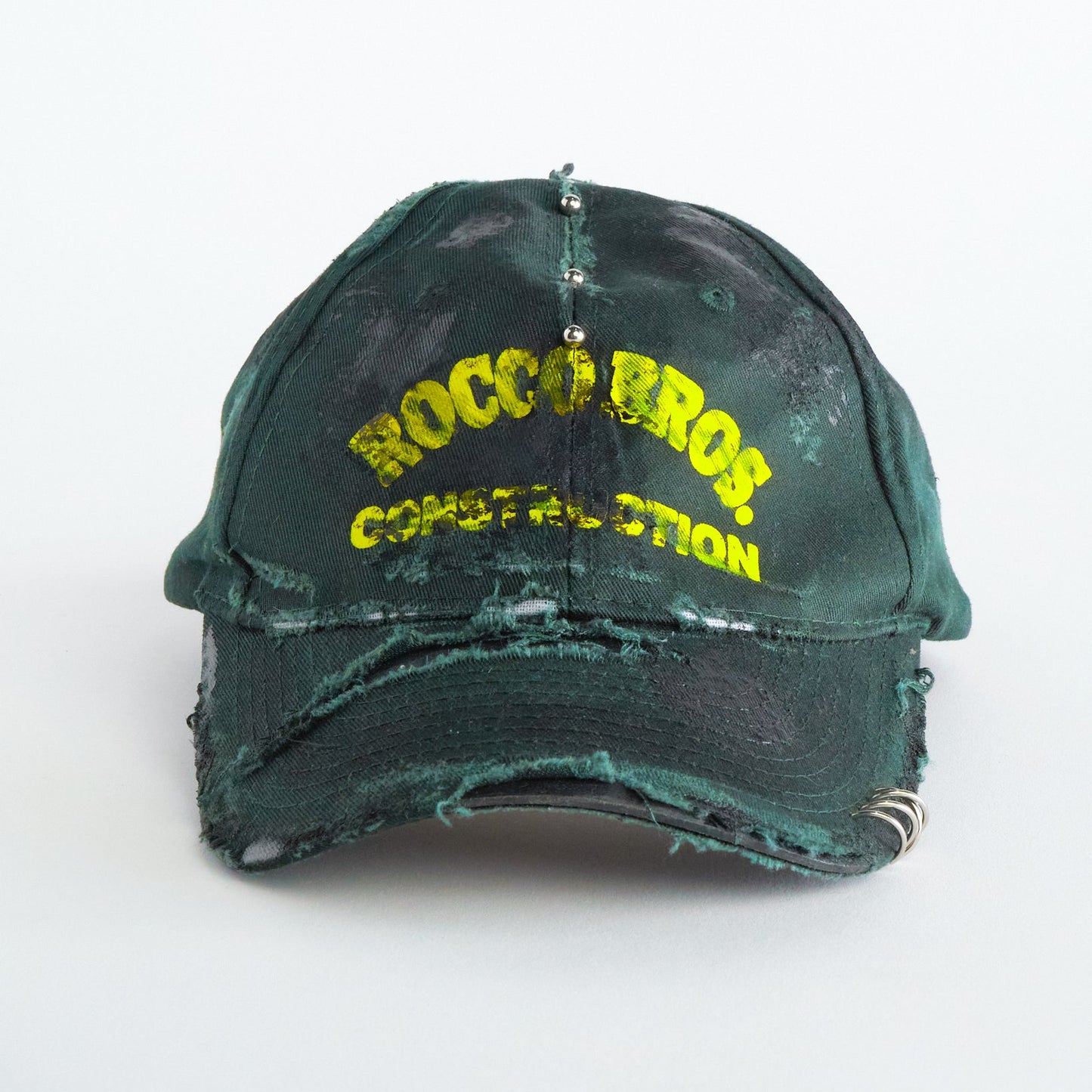 Front of ASTROBOI* Rocco Bros green construction hat with black grease distressing, stainless steel piercings, adjustable strap, handmade in NYC.
