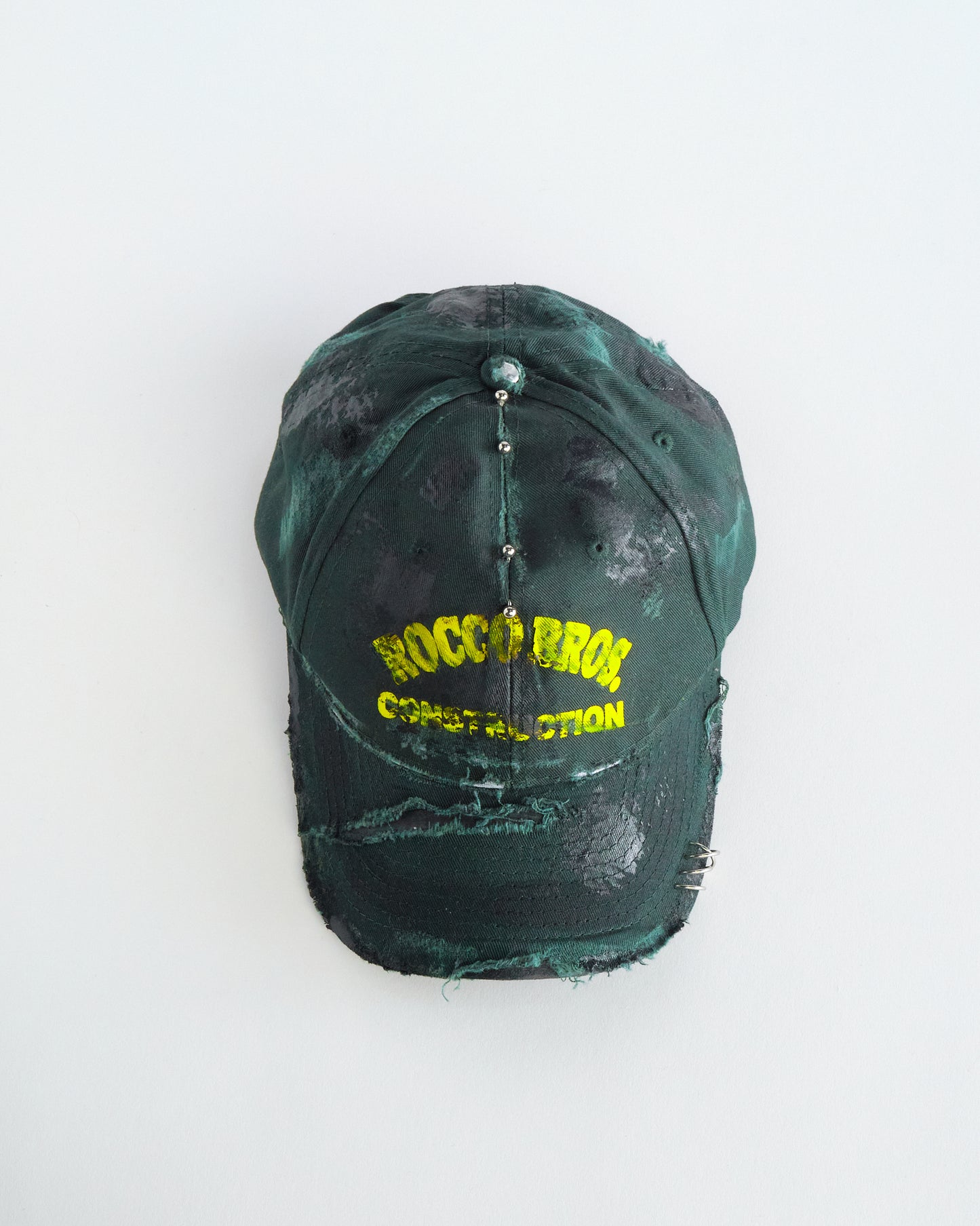 Top of ASTROBOI* Rocco Bros green construction hat with black grease distressing, stainless steel piercings, adjustable strap, handmade in NYC.