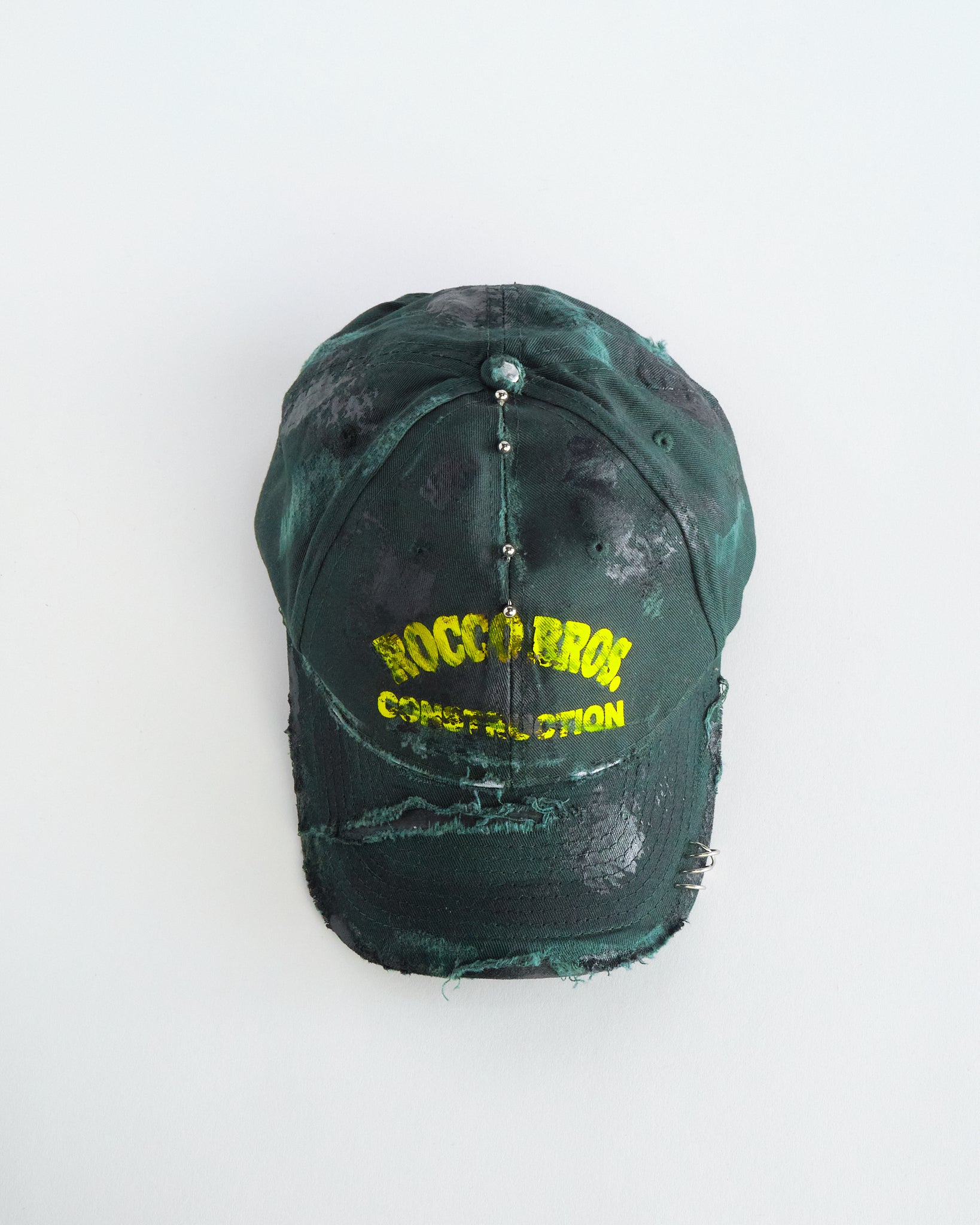 Top of ASTROBOI* Rocco Bros green construction hat with black grease distressing, stainless steel piercings, adjustable strap, handmade in NYC.