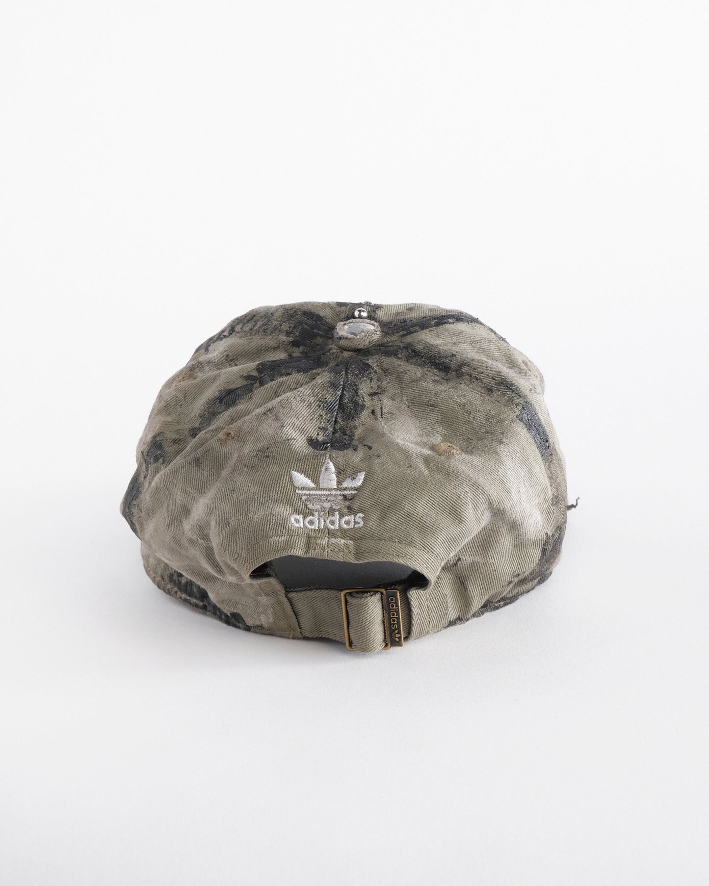 Back of ASTROBOI* x Adidas tan distressed hat with black paint detailing, Adidas logo at front, and stainless steel piercings, customized in NYC.