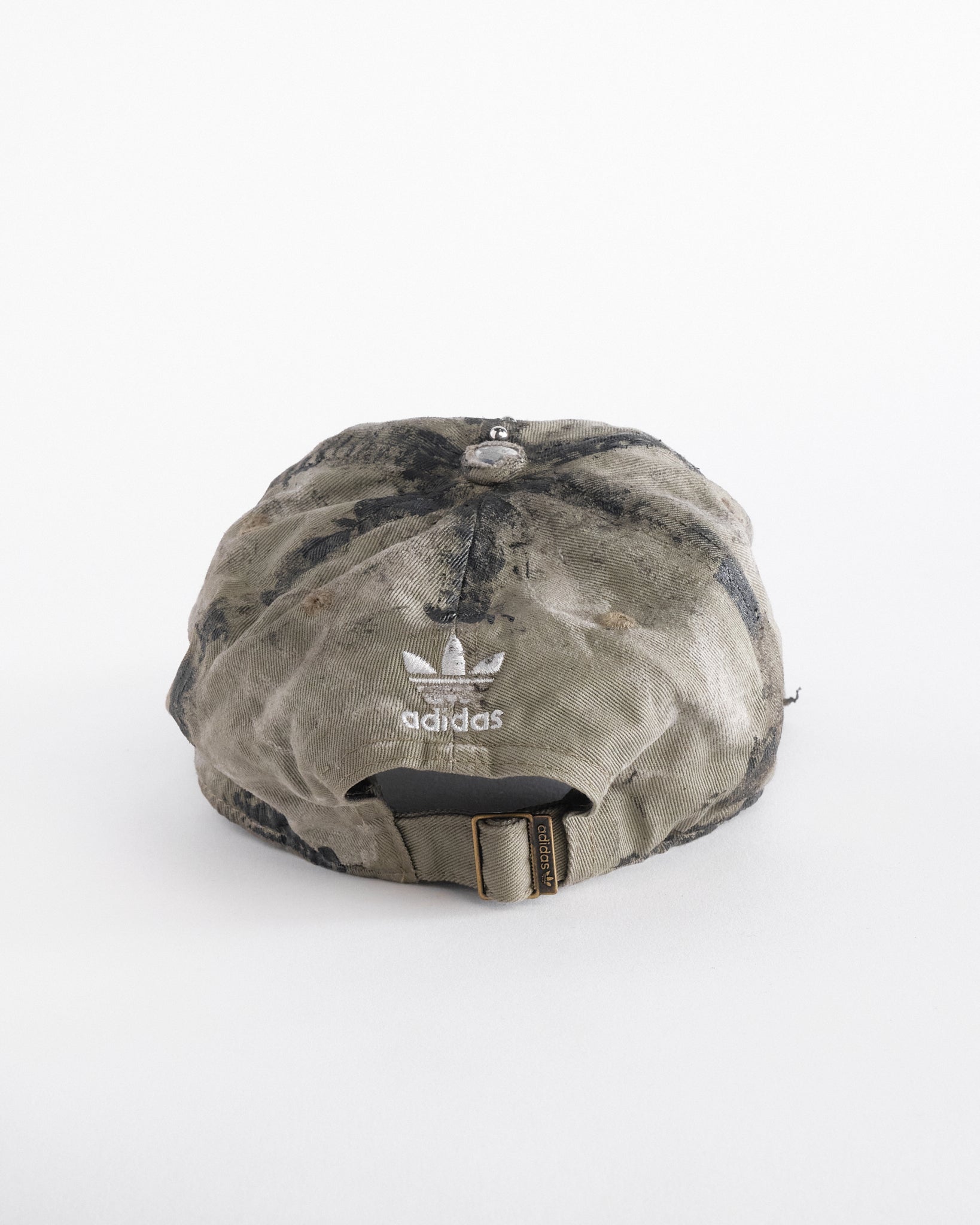 Back of ASTROBOI* x Adidas tan distressed hat with black paint detailing, Adidas logo at front, and stainless steel piercings, customized in NYC.