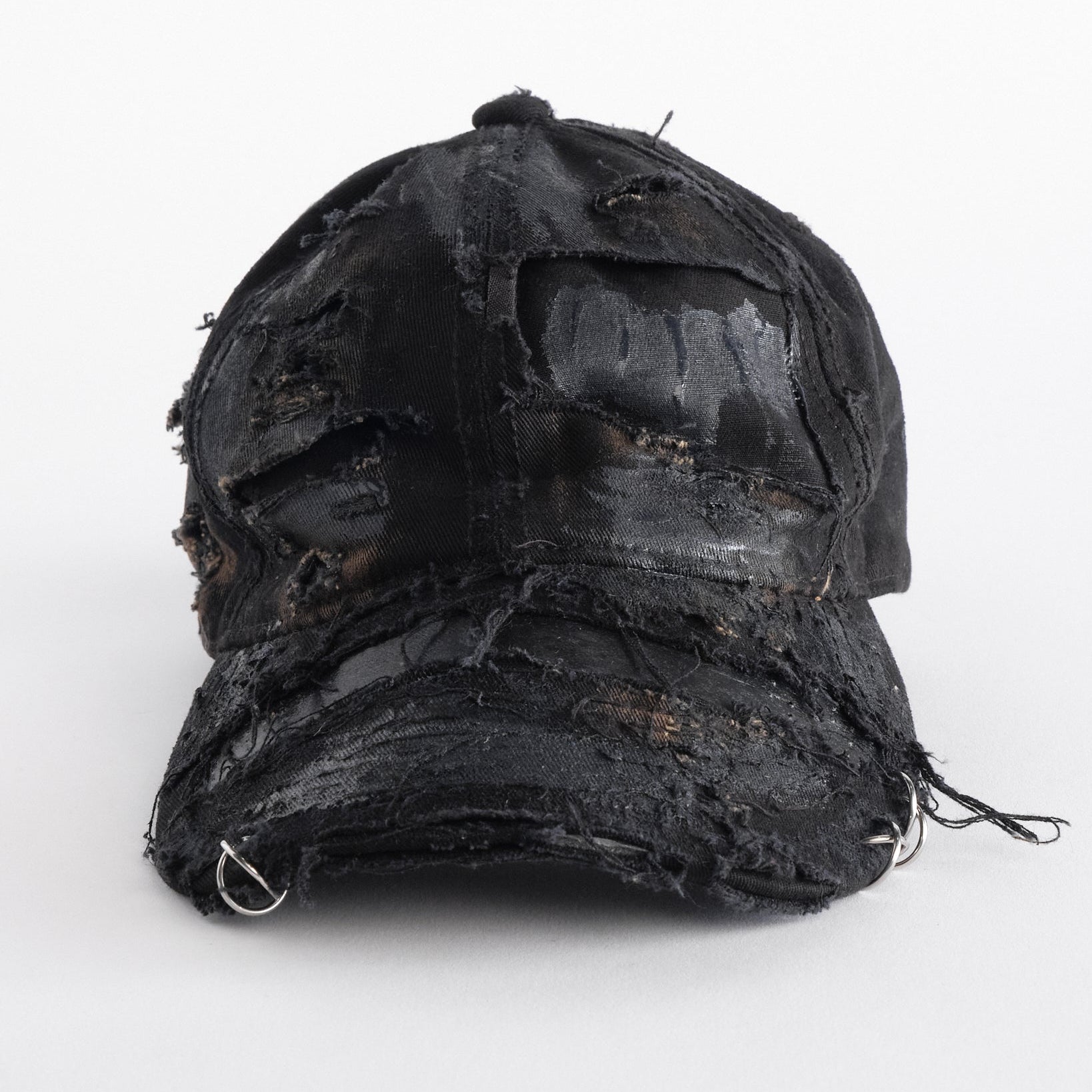 Front of ASTROBOI* black distressed denim hat with faded finish, layered black paint, and sterling silver piercings, customized in NYC.