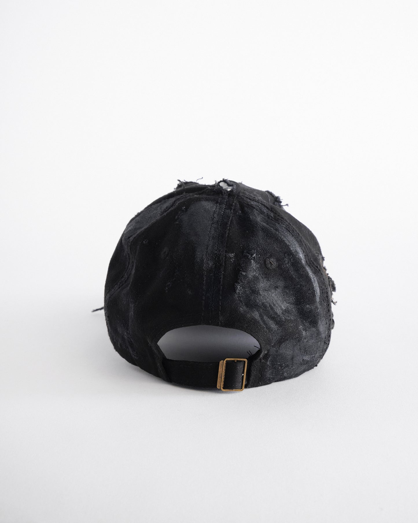Back of ASTROBOI* black distressed denim hat with faded finish, layered black paint, and sterling silver piercings, customized in NYC.
