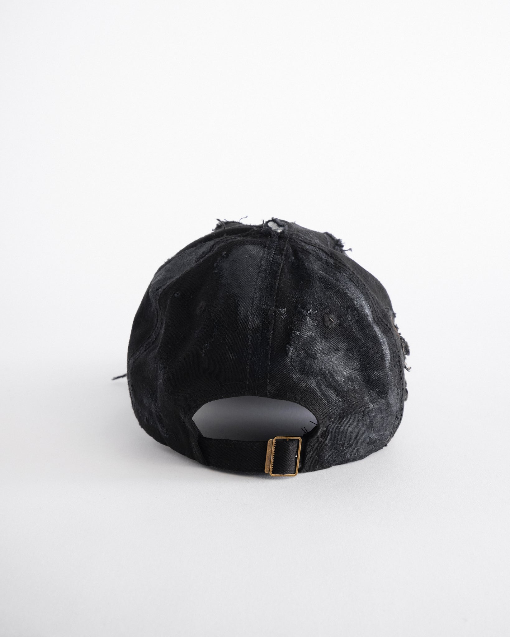 Back of ASTROBOI* black distressed denim hat with faded finish, layered black paint, and sterling silver piercings, customized in NYC.