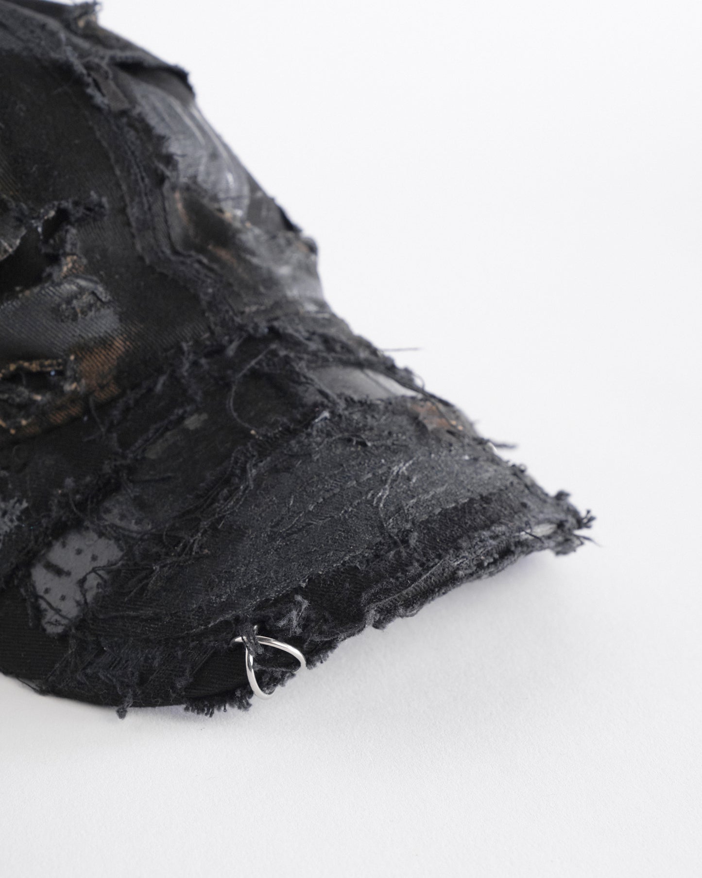 Front visor detail ASTROBOI* black distressed denim hat with faded finish, layered black paint, and sterling silver piercings, customized in NYC.