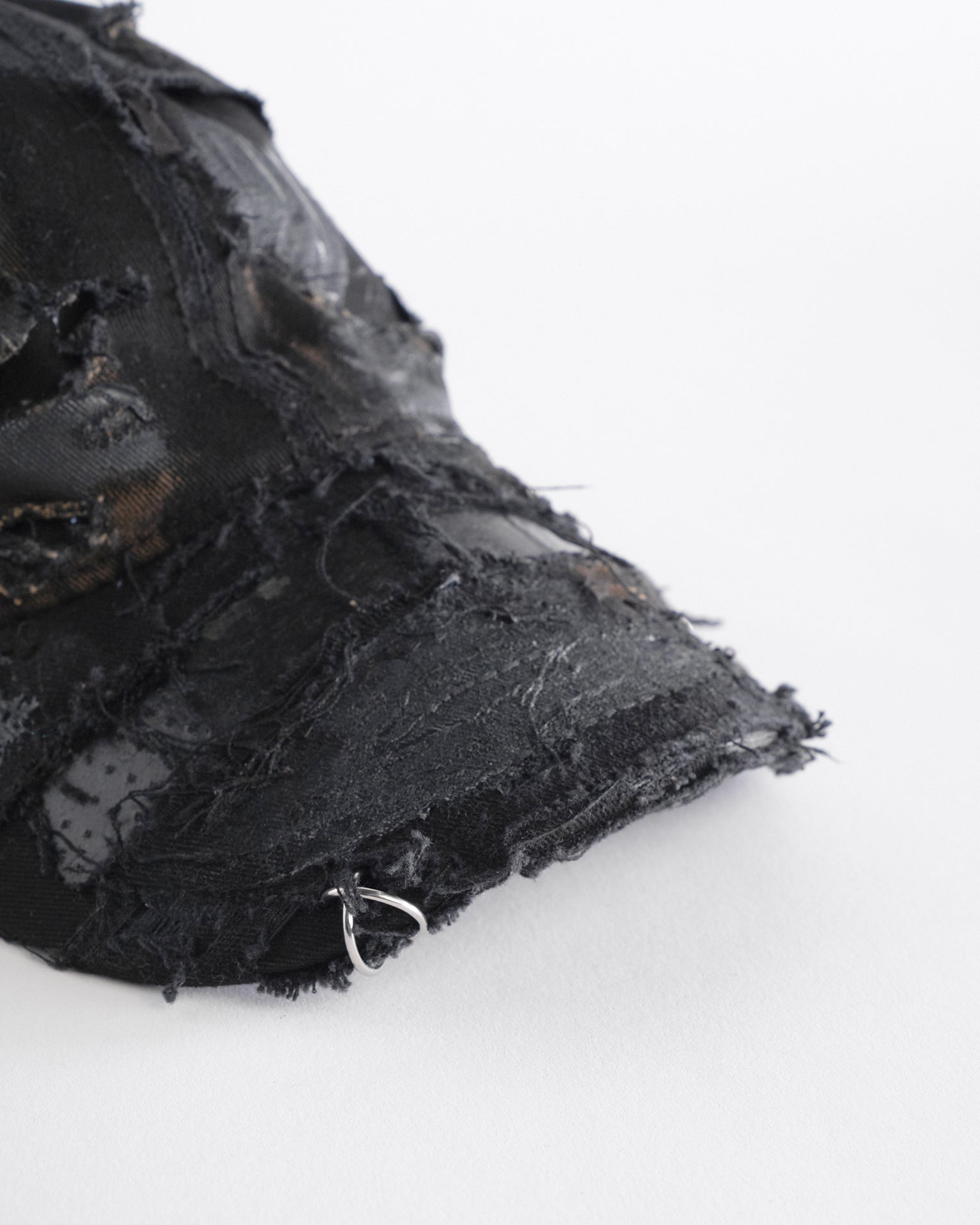 Front visor detail ASTROBOI* black distressed denim hat with faded finish, layered black paint, and sterling silver piercings, customized in NYC.