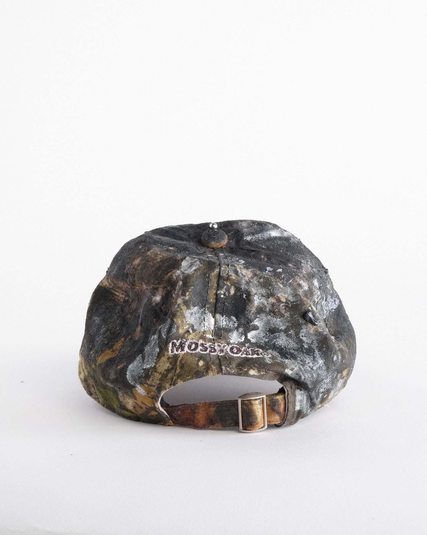 Back of ASTROBOI* x Mossy Oak brown real tree camo half visor hat with rhinestone resin logo and stainless steel piercings.