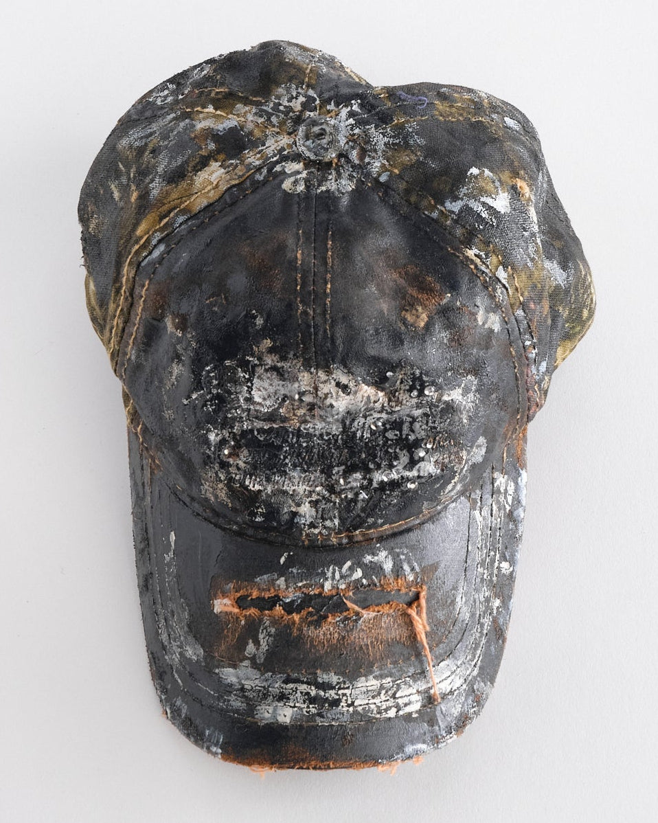 Front top of ASTROBOI* x Mossy Oak brown RealTree camo hat with rhinestones, distressed paint details, and leather visor, adjustable fit.