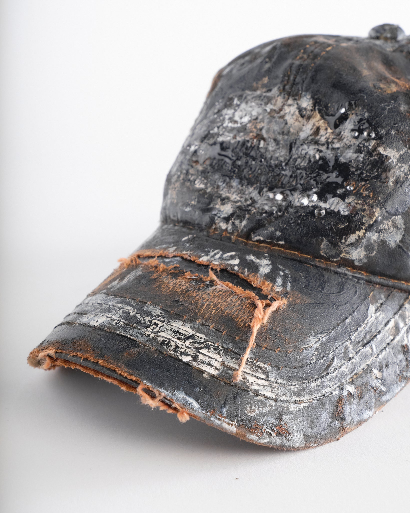 Visor detail of ASTROBOI* x Mossy Oak brown RealTree camo hat with rhinestones, distressed paint details, and leather visor, adjustable fit.