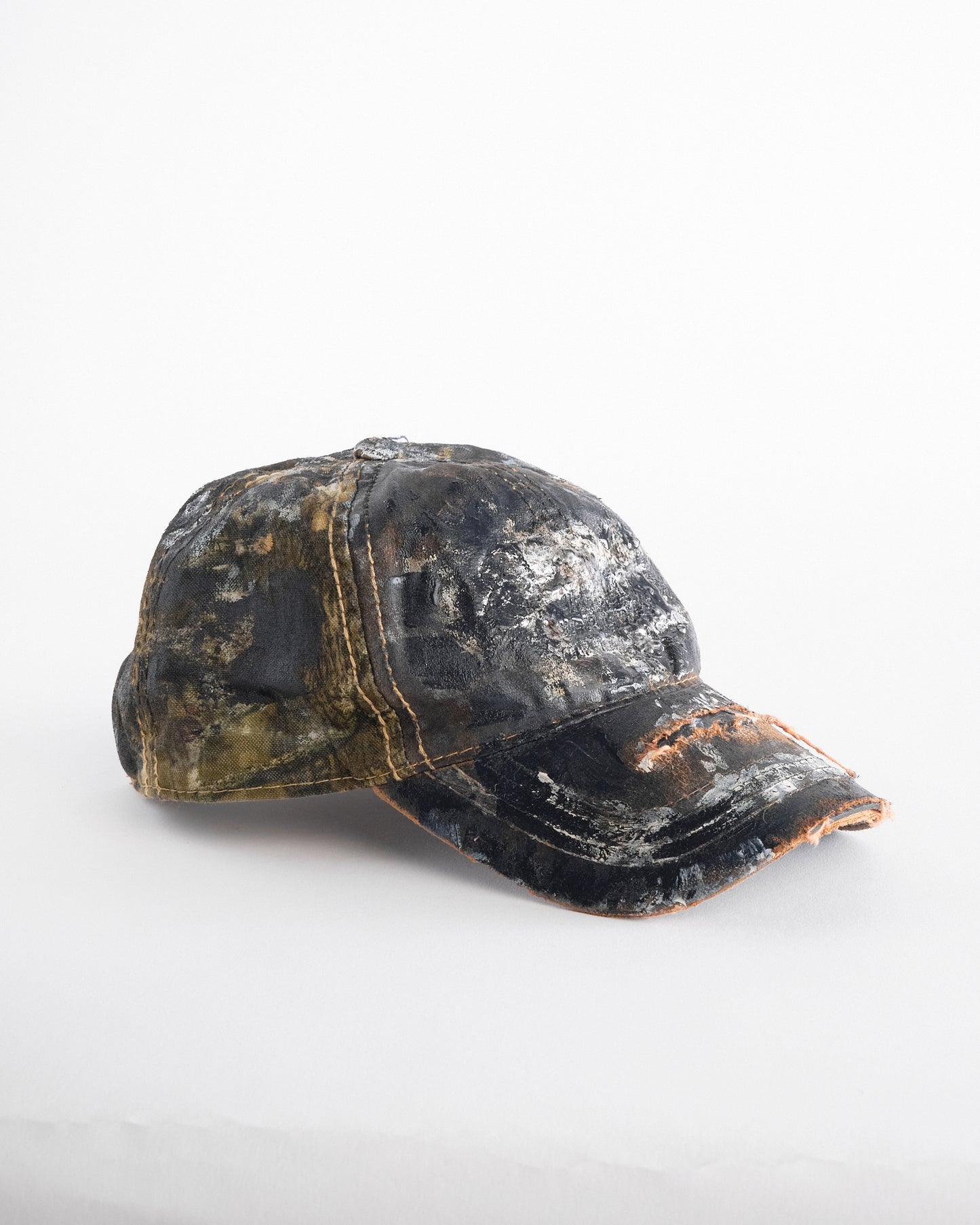 Right of ASTROBOI* x Mossy Oak brown RealTree camo hat with rhinestones, distressed paint details, and leather visor, adjustable fit.