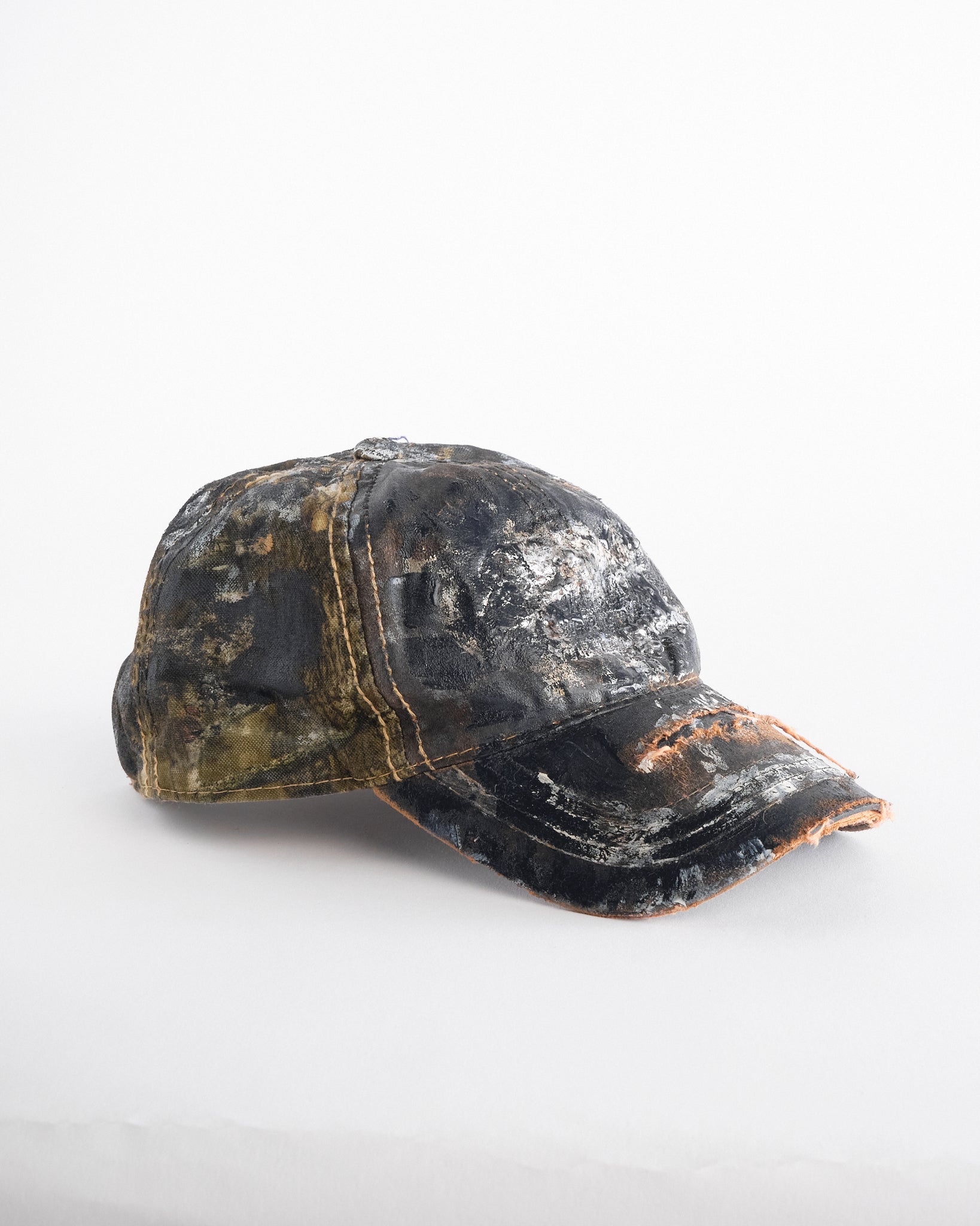 Right of ASTROBOI* x Mossy Oak brown RealTree camo hat with rhinestones, distressed paint details, and leather visor, adjustable fit.