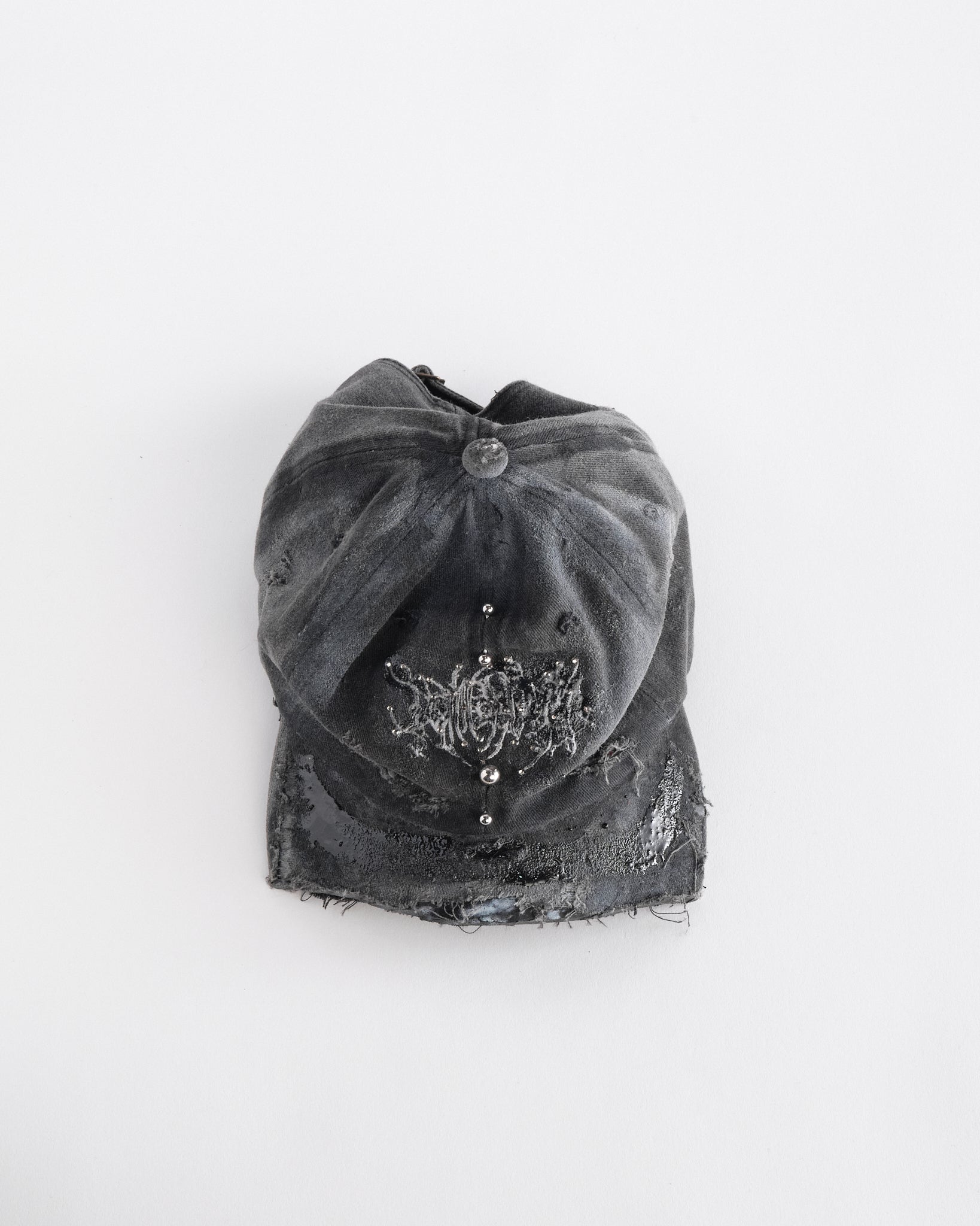 Front top side of ASTROBOI* Chalk black distressed half-visor hat with white airbrush detailing, rhinestones, resin accents, and stainless steel piercings.