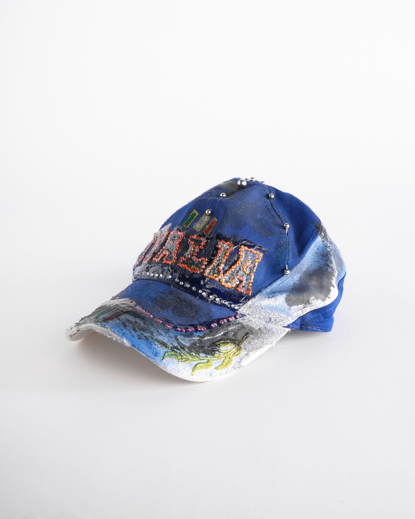 Front left of Upcycled blue and white ASTROBOI* ‘ITALIA’ hat with rhinestones, resin, custom paint, and stainless steel piercings, handcrafted in NYC.