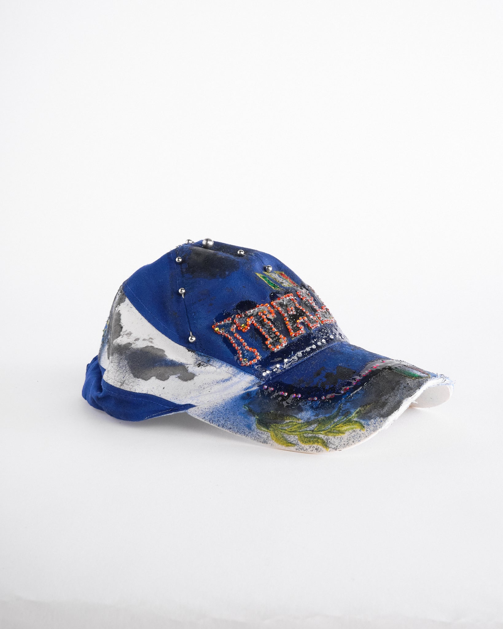 Right of Upcycled blue and white ASTROBOI* ‘ITALIA’ hat with rhinestones, resin, custom paint, and stainless steel piercings, handcrafted in NYC.