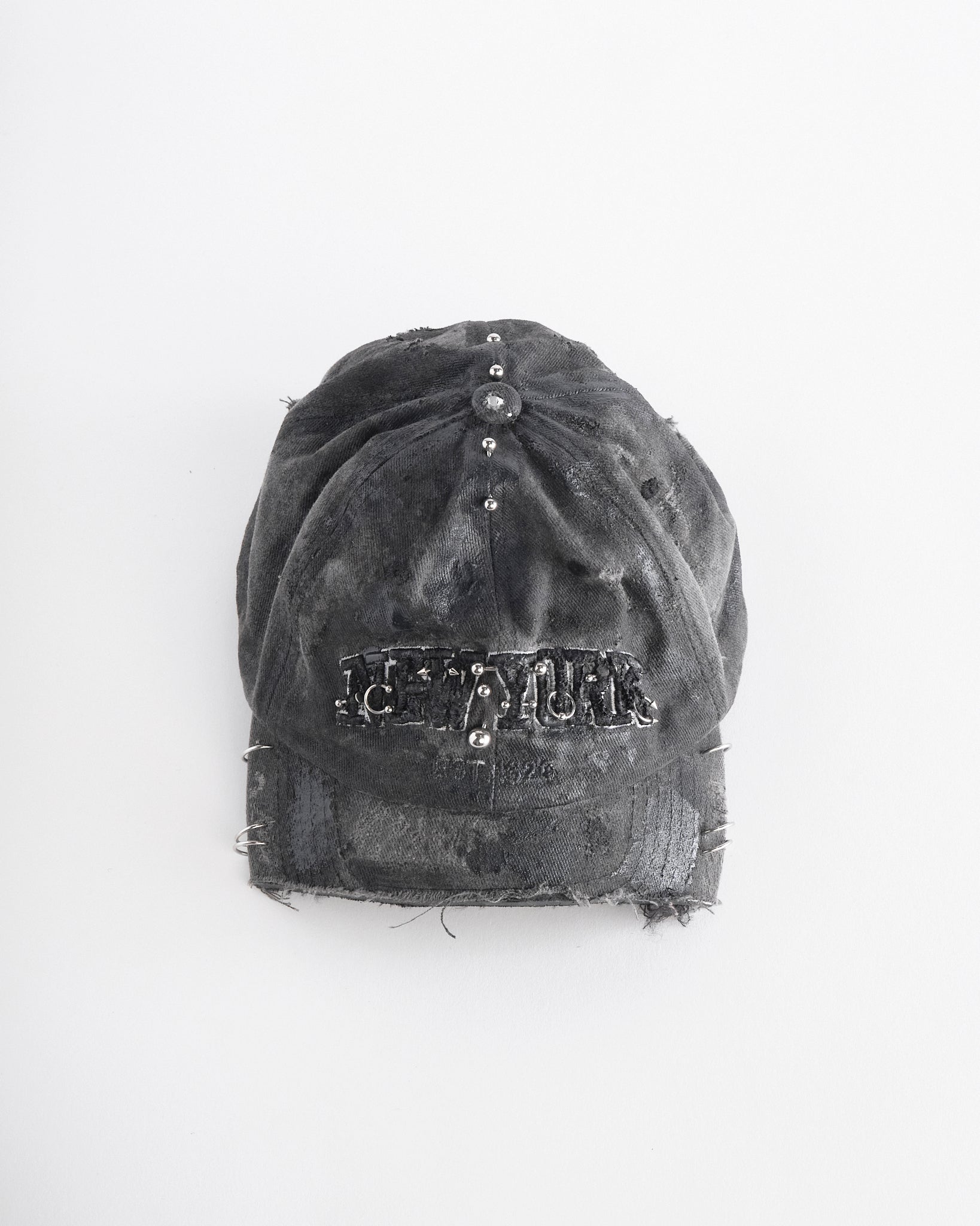 Front top of Black half-visor “New York” hat with embroidered front logo, stainless steel piercings, and an adjustable strap.