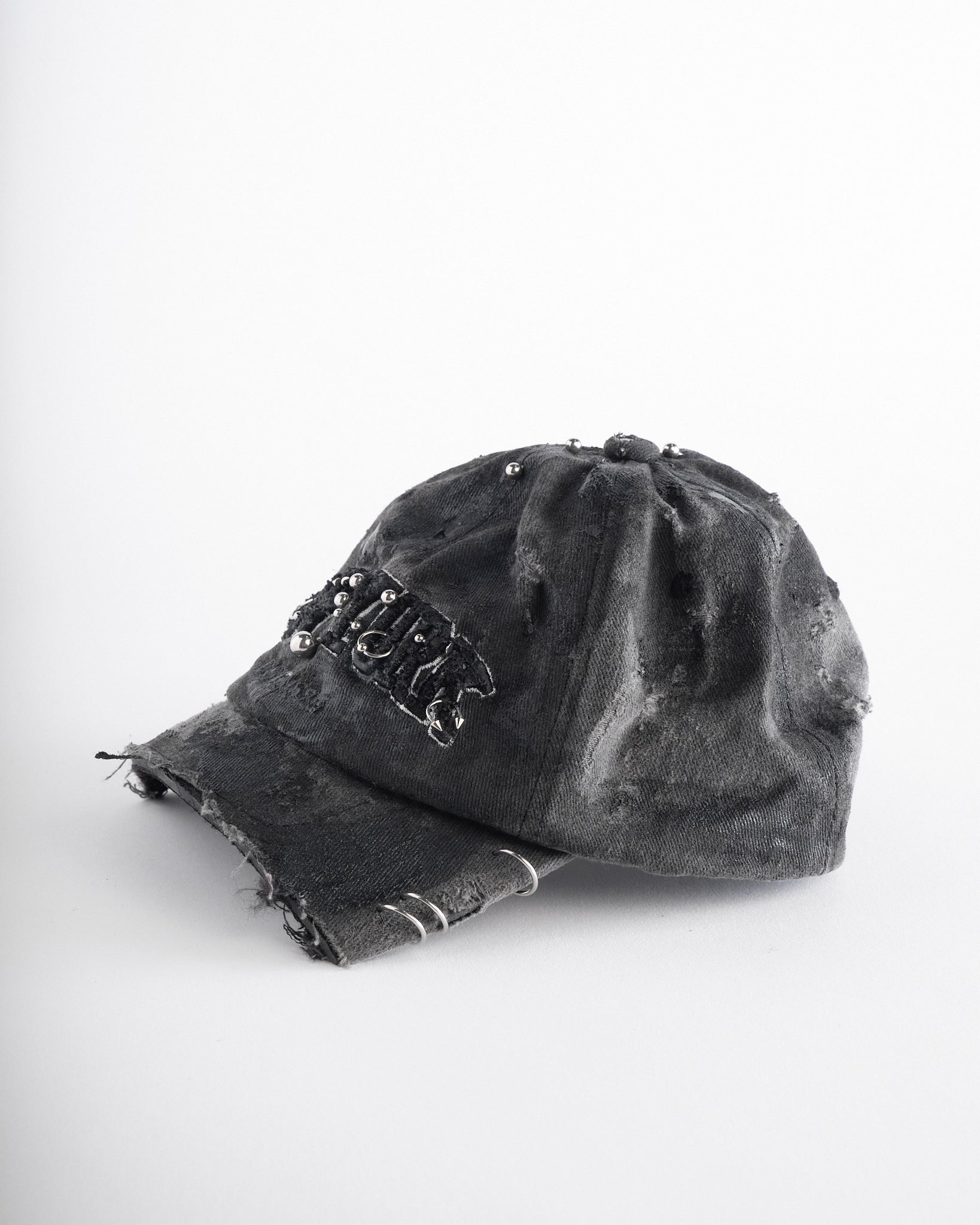 Left of of Black half-visor “New York” hat with embroidered front logo, stainless steel piercings, and an adjustable strap.