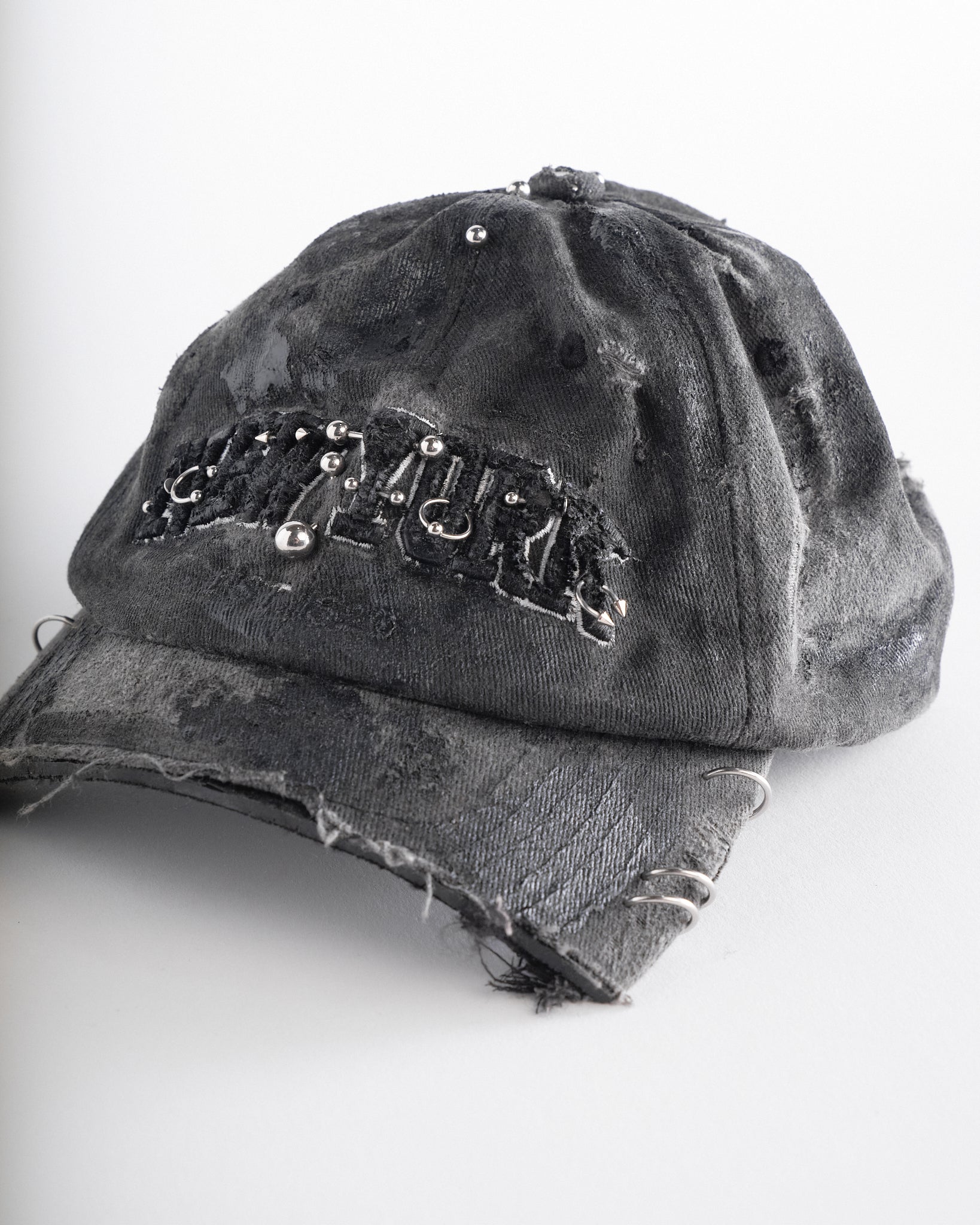 Left front detail of Black half-visor “New York” hat with embroidered front logo, stainless steel piercings, and an adjustable strap.