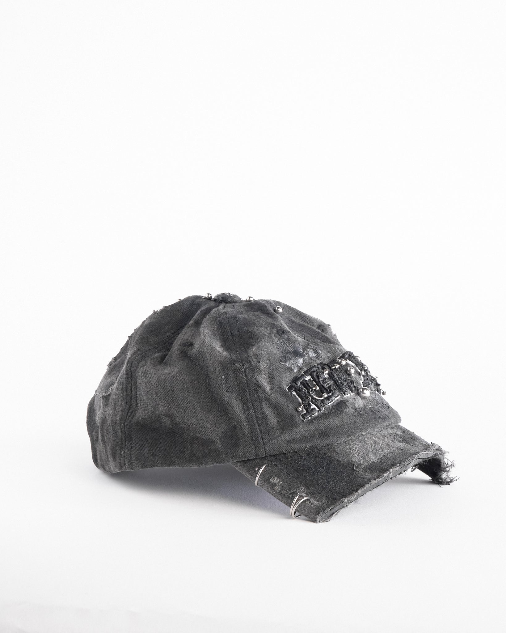 Right of Black half-visor “New York” hat with embroidered front logo, stainless steel piercings, and an adjustable strap.