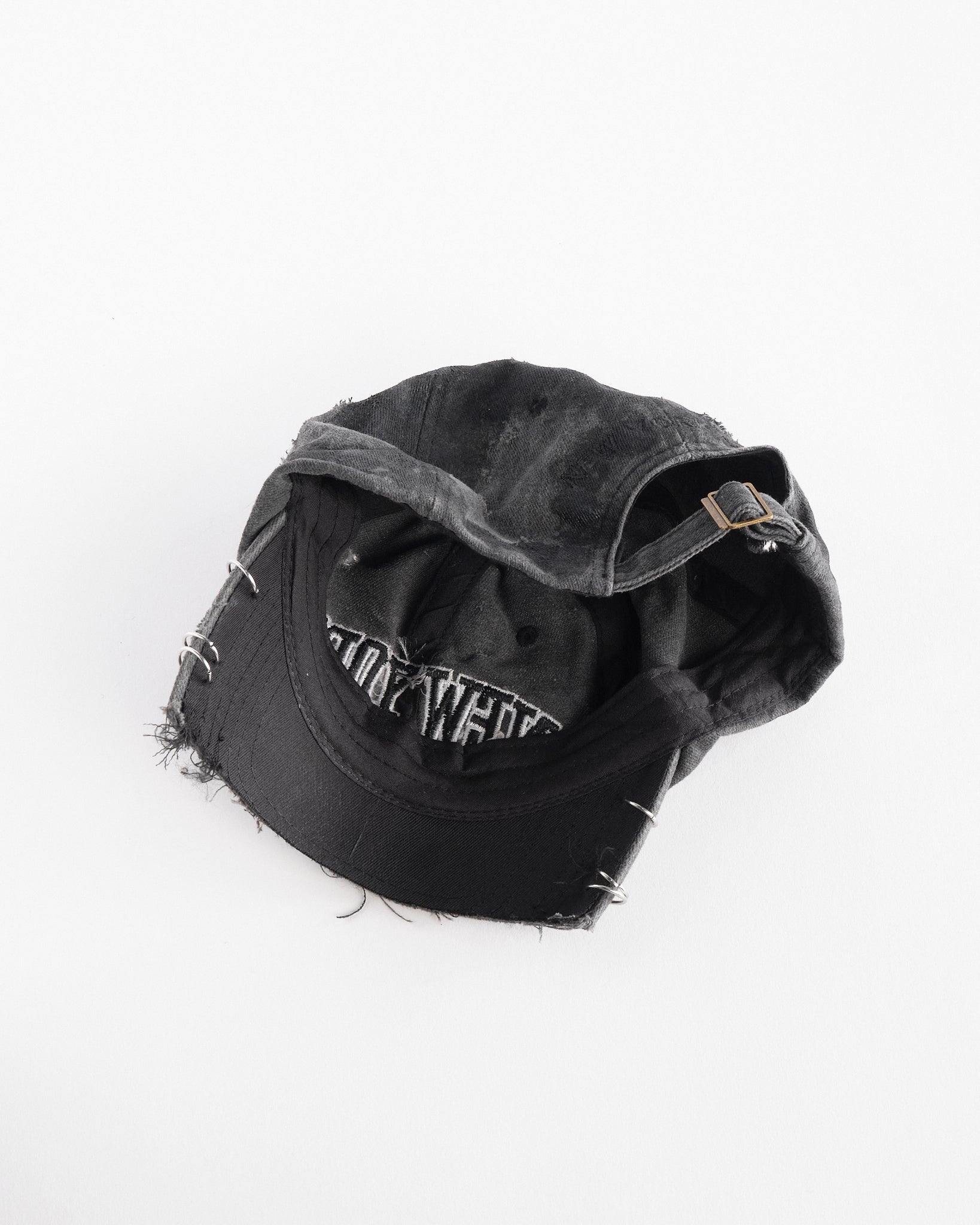 Interior side of Black half-visor “New York” hat with embroidered front logo, stainless steel piercings, and an adjustable strap.