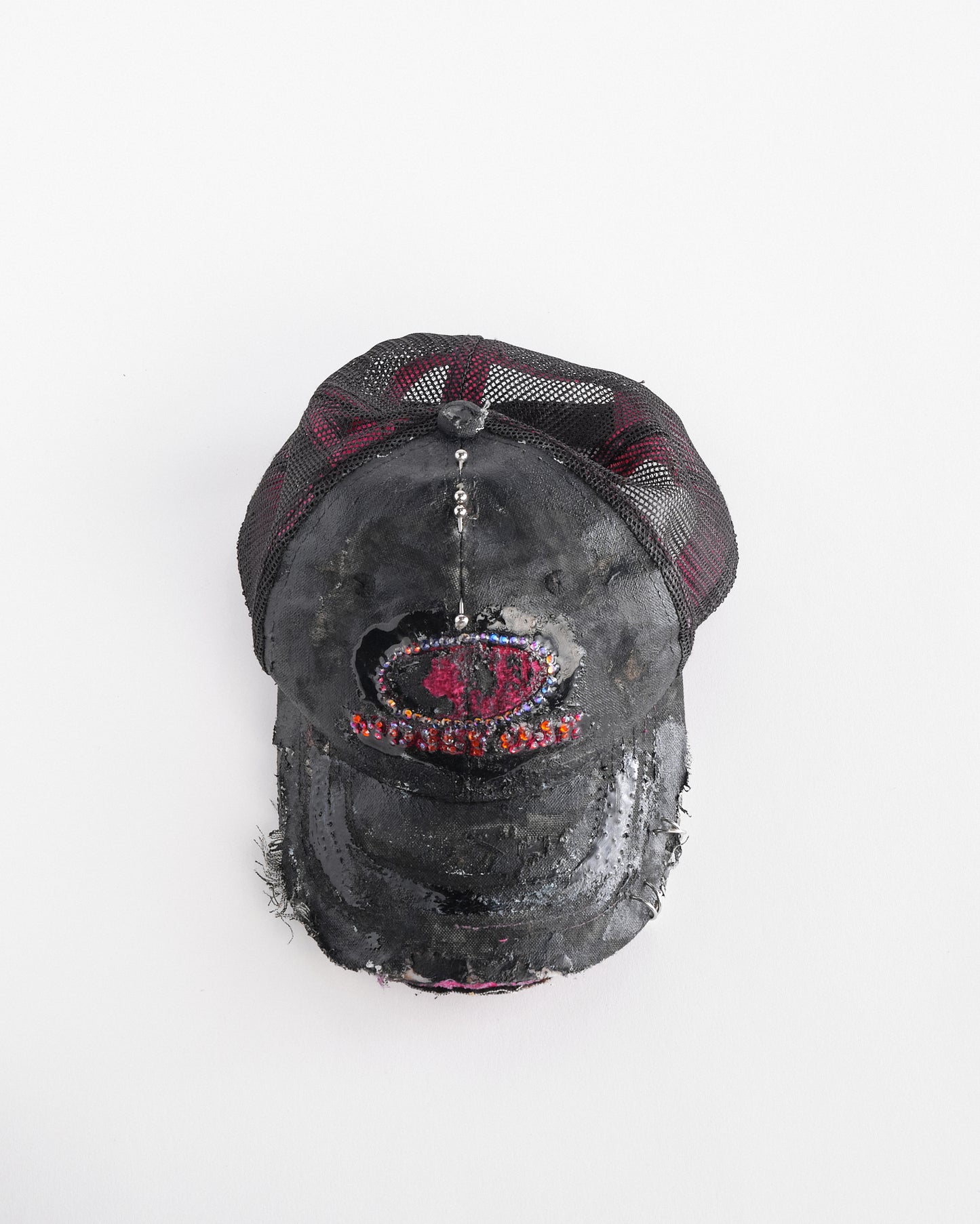Top front of ASTROBOI* x Mossy Oak black and pink distressed rhinestone hat with resin logo and mesh back panel