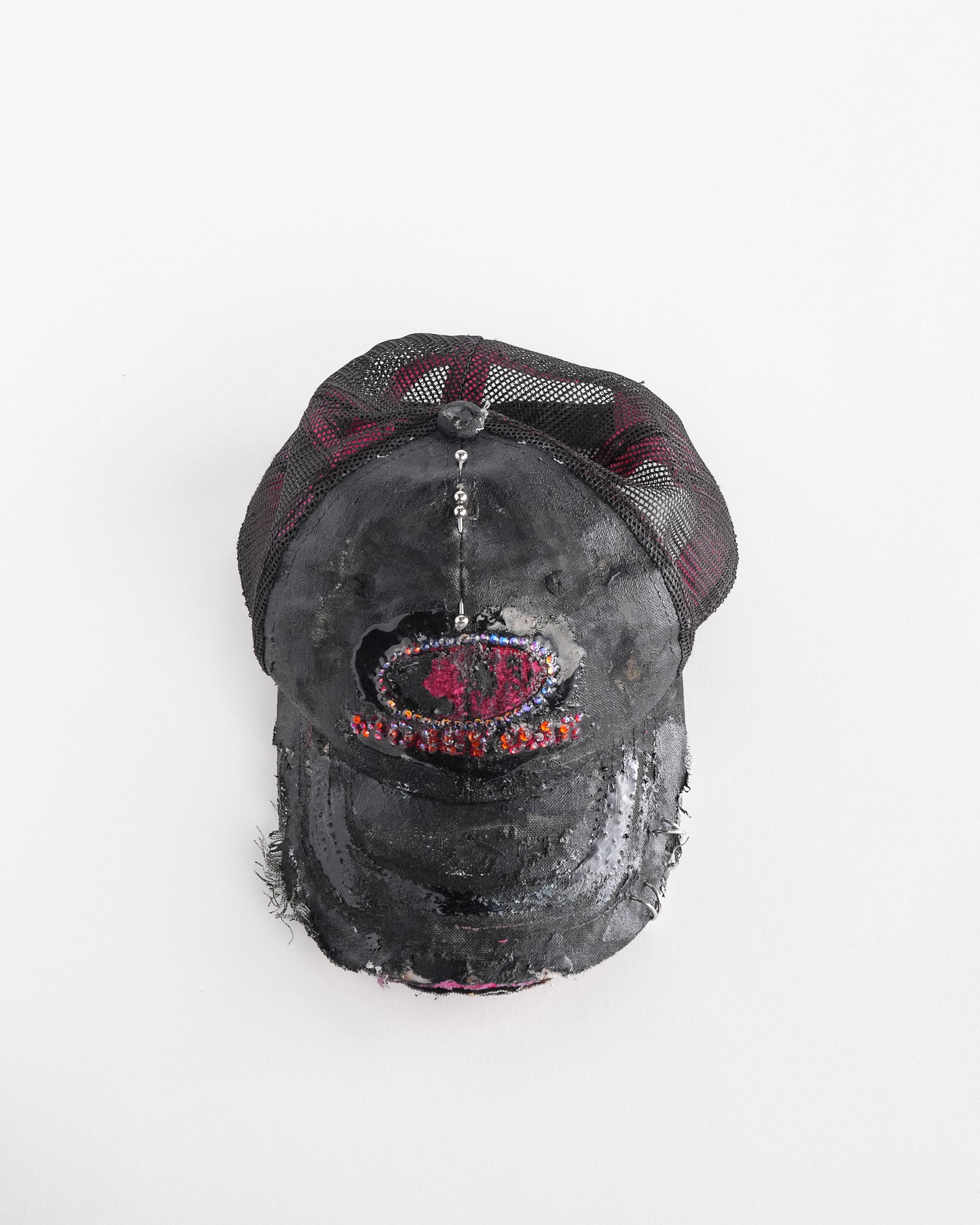 Top front of ASTROBOI* x Mossy Oak black and pink distressed rhinestone hat with resin logo and mesh back panel