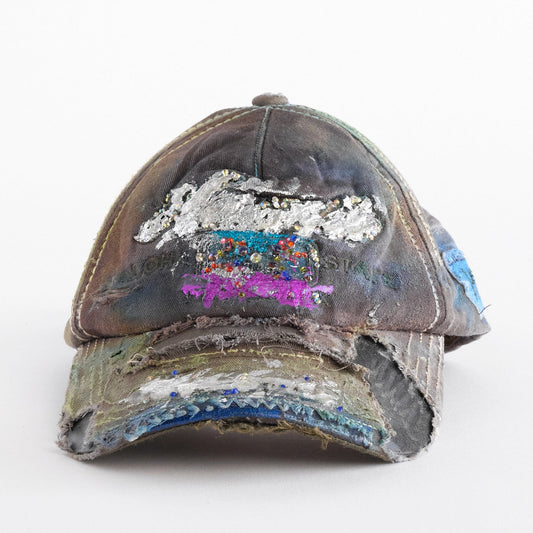 Front of Brown-green ASTROBOI* hat featuring a metallic Hawaii logo with multicolored rhinestones, distressed visor, and resin-coated safety pin detail.