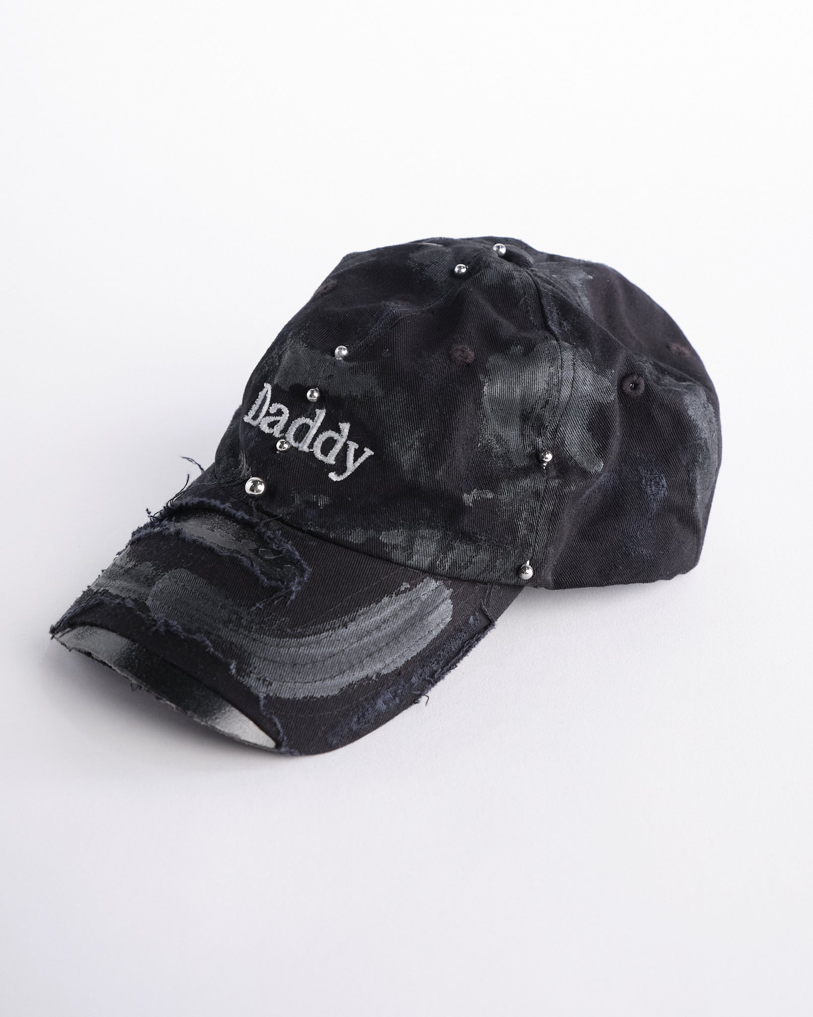 Left side of side of Black distressed ASTROBOI* ‘Daddy’ hat with custom paint detailing and stainless steel piercings, handcrafted in NYC.