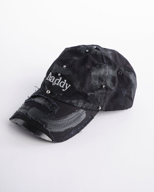 Left side of side of Black distressed ASTROBOI* ‘Daddy’ hat with custom paint detailing and stainless steel piercings, handcrafted in NYC.
