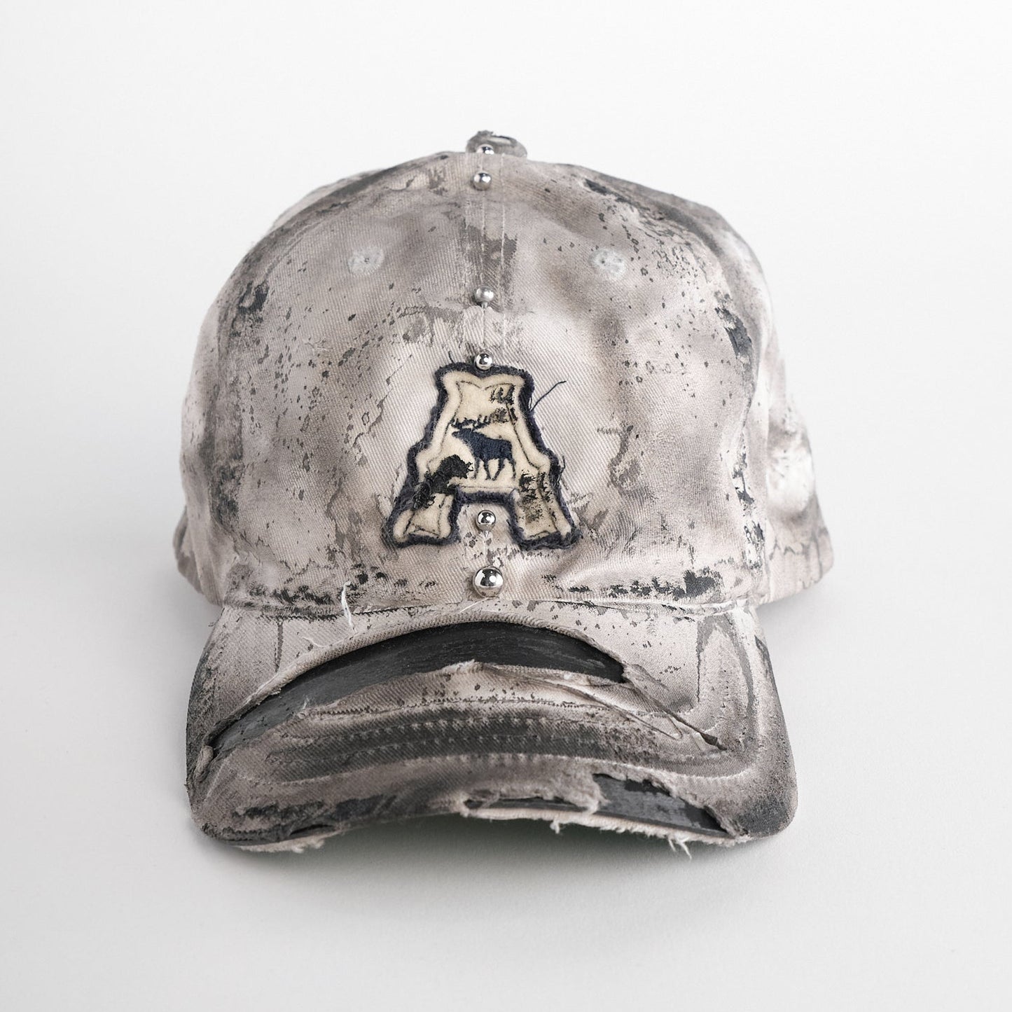 Front of Off-white and black faded ASTROBOI* x Abercrombie hat with custom paint treatment and stainless steel piercing, handmade in NYC.